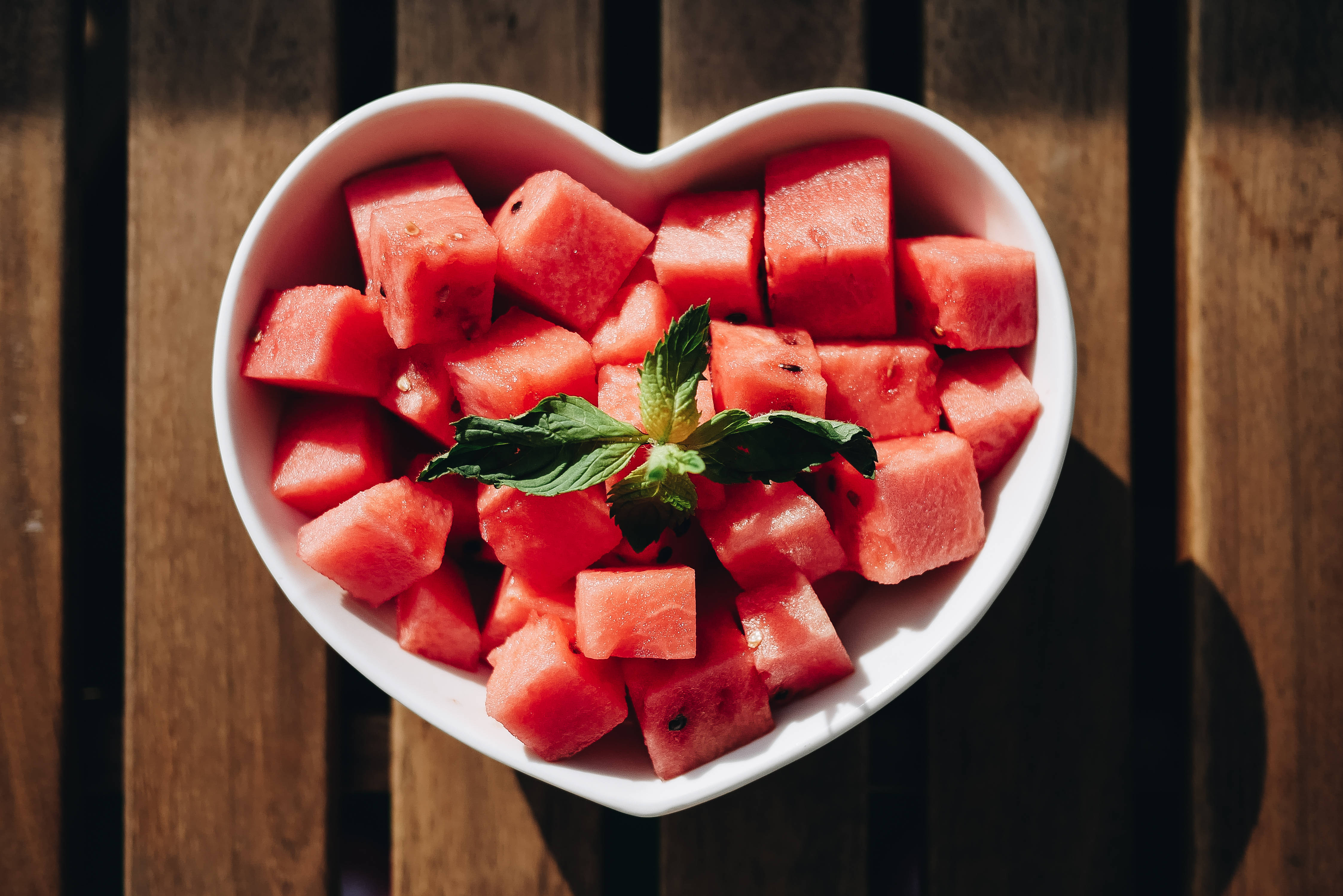 white heart-shaped bowl, juicy red watermelon cubes, sprig of mint, 4K Desktop Wallpaper