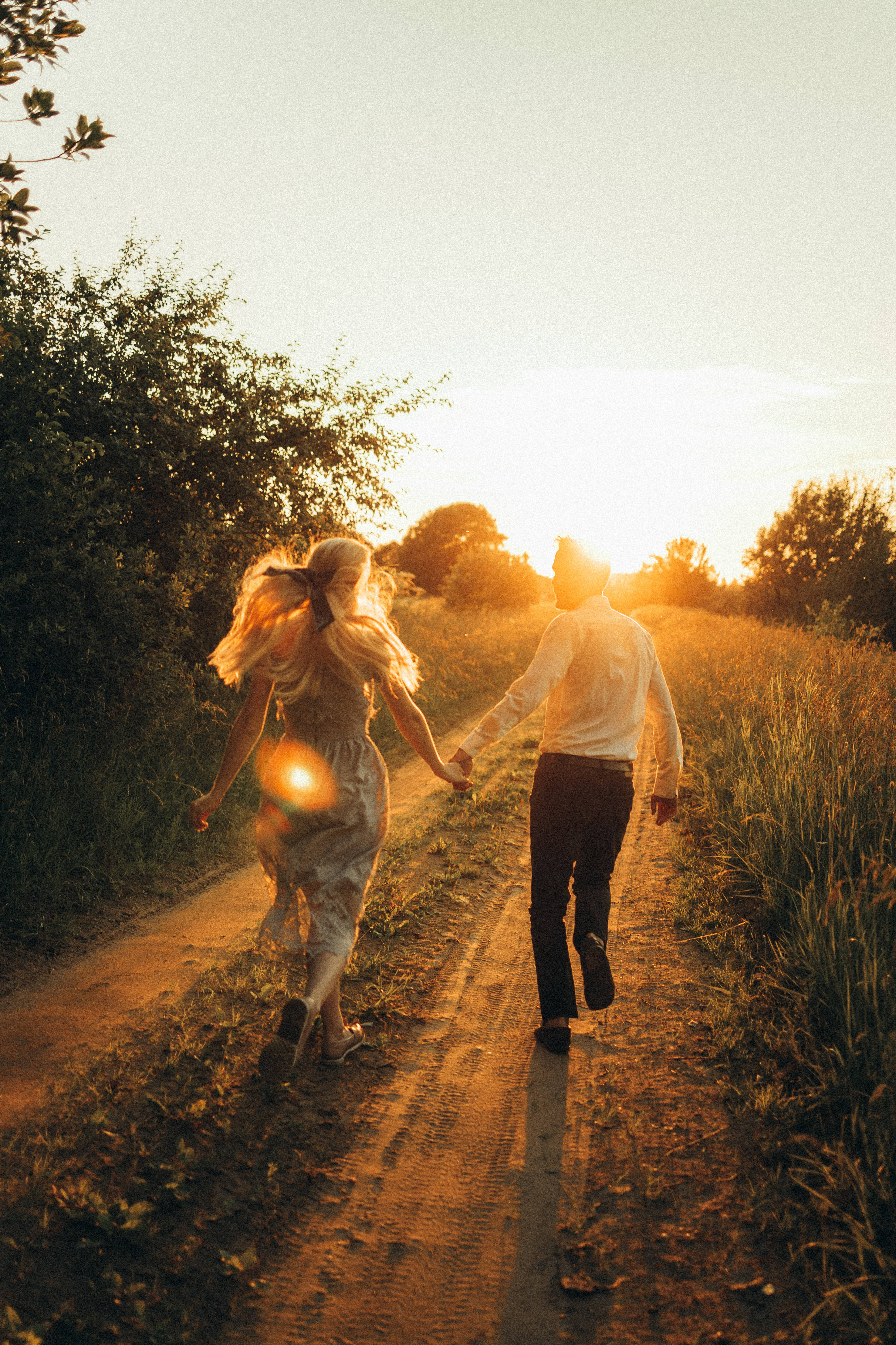 Lovers Running Towards The Sun, golden sunset light, dirt path, 5K Phone Wallpaper
