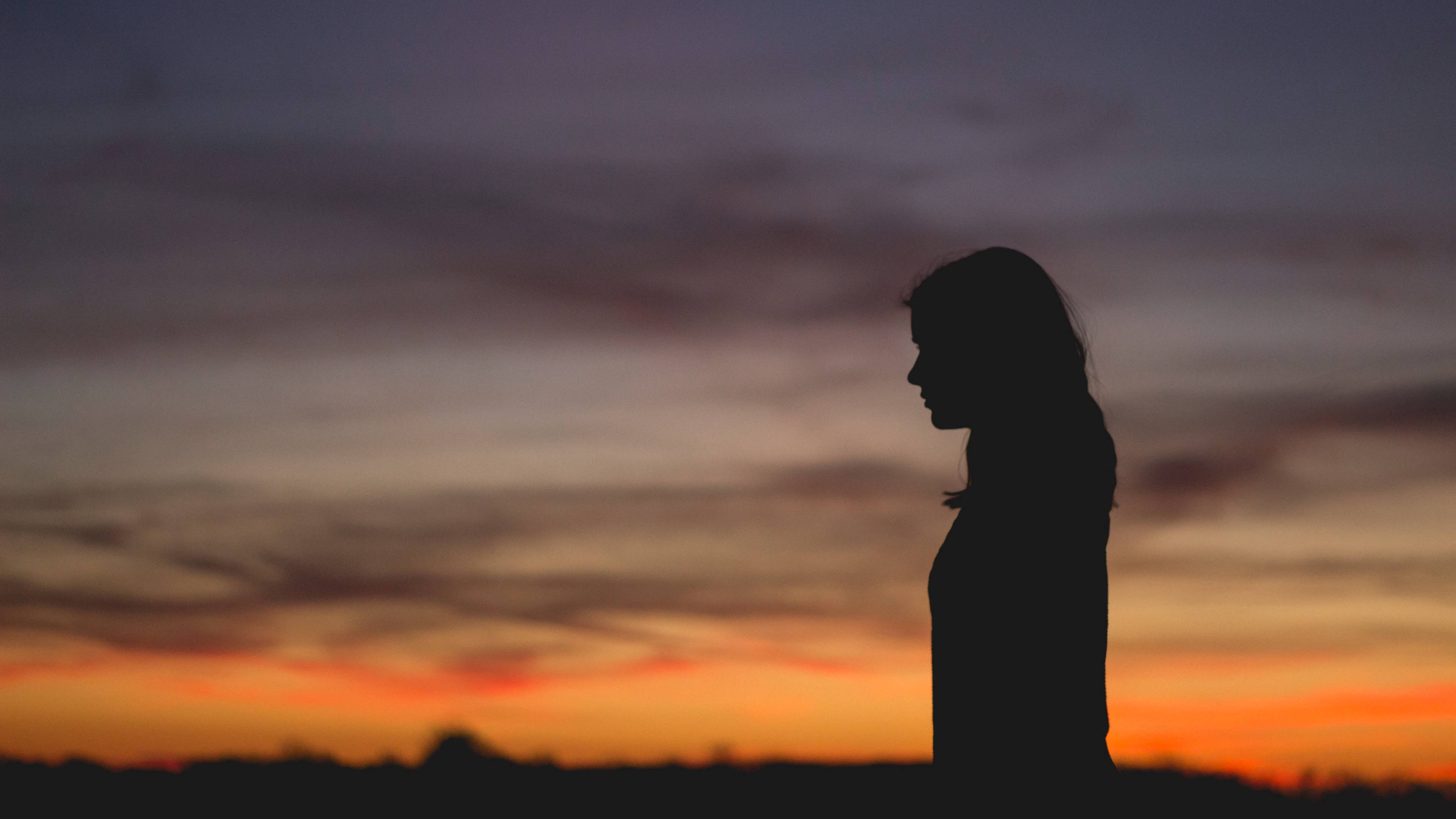 woman's silhouette, vibrant sunset sky, orange and purple hues, 4K Desktop Wallpaper