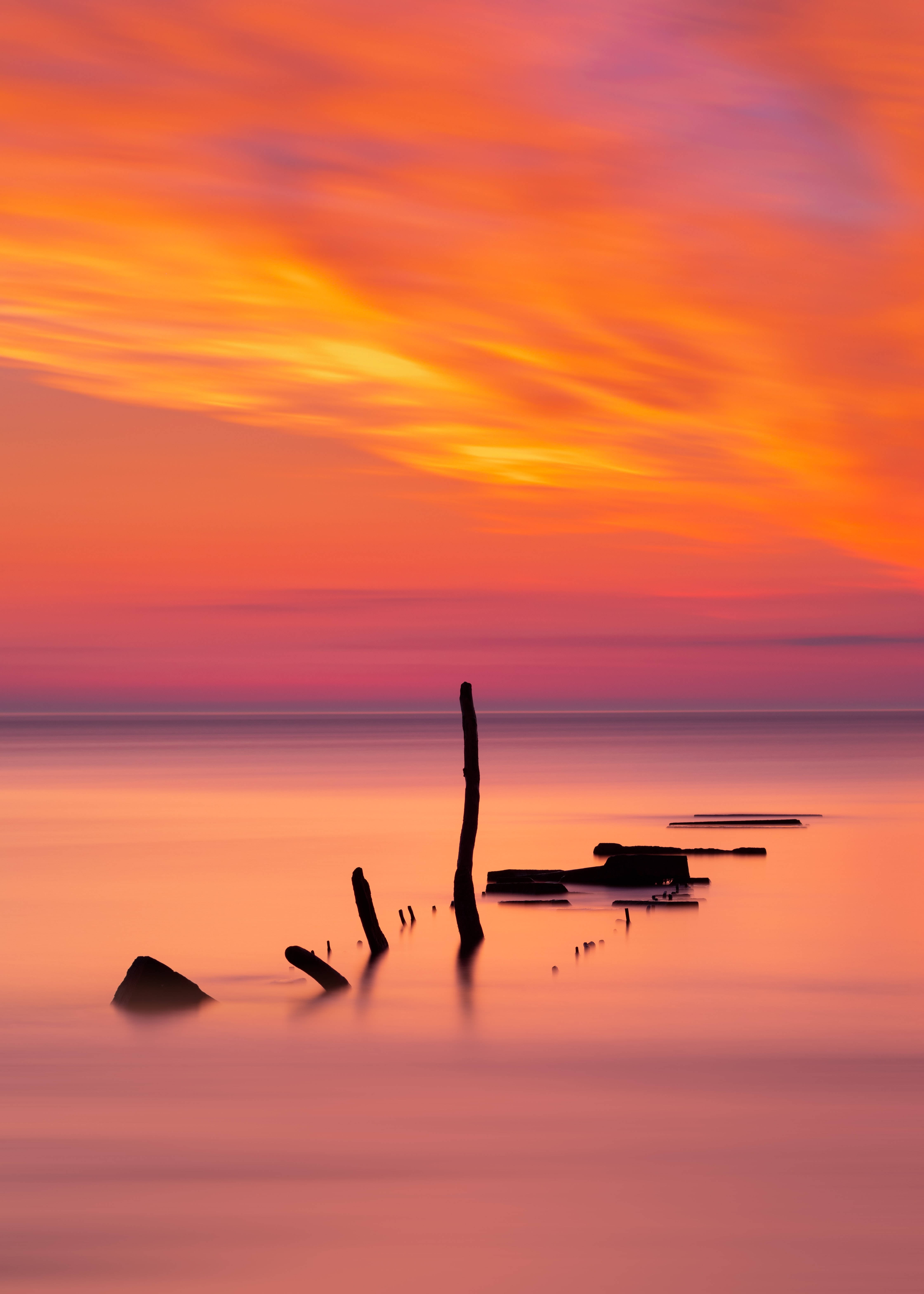 ocean sunset, fiery orange and pink sunset sky, silhouetted driftwood, 5K Phone Wallpaper
