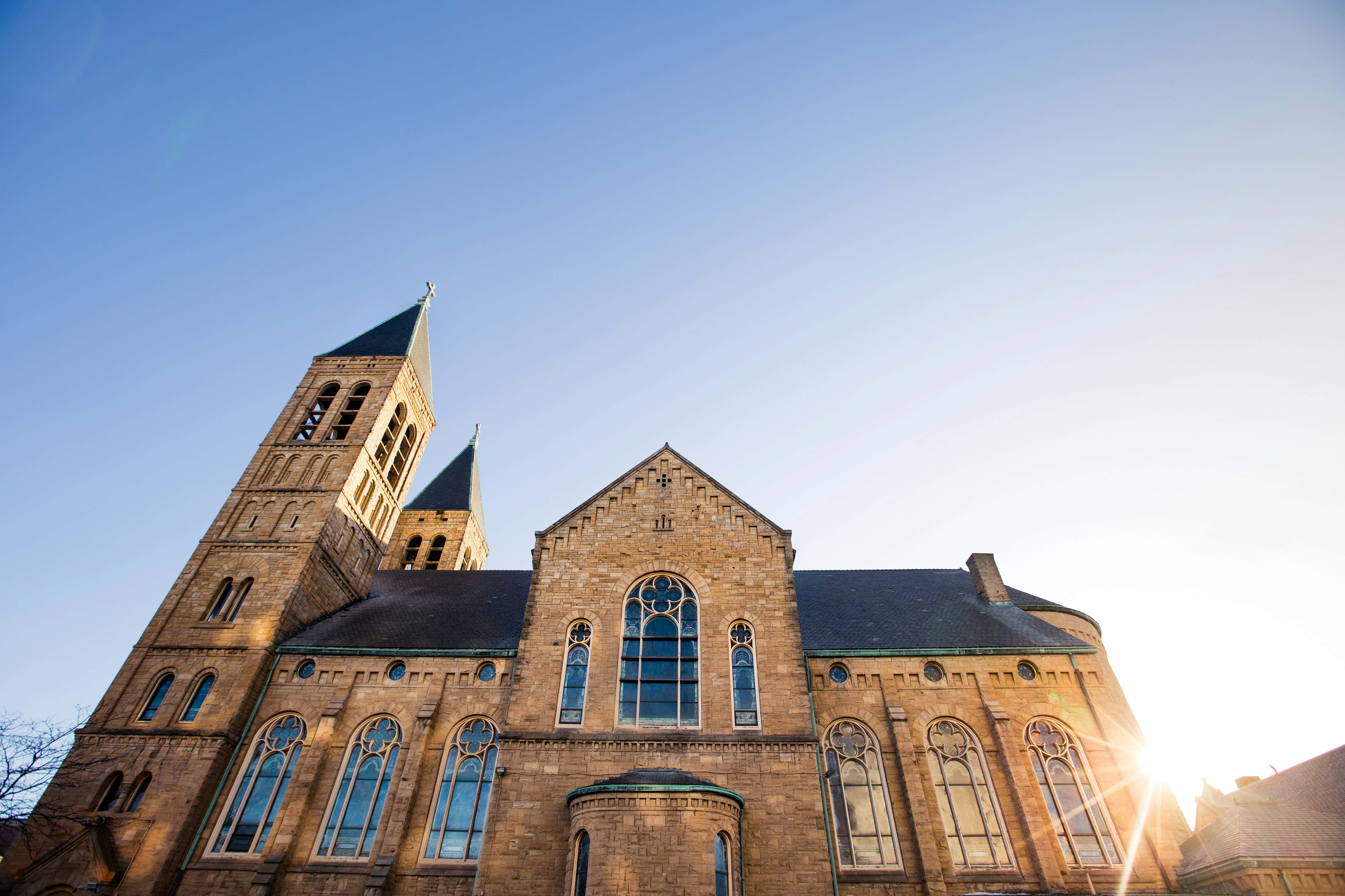 sunlit church facade, twin spires, arched stained glass windows, 5K Desktop Wallpaper