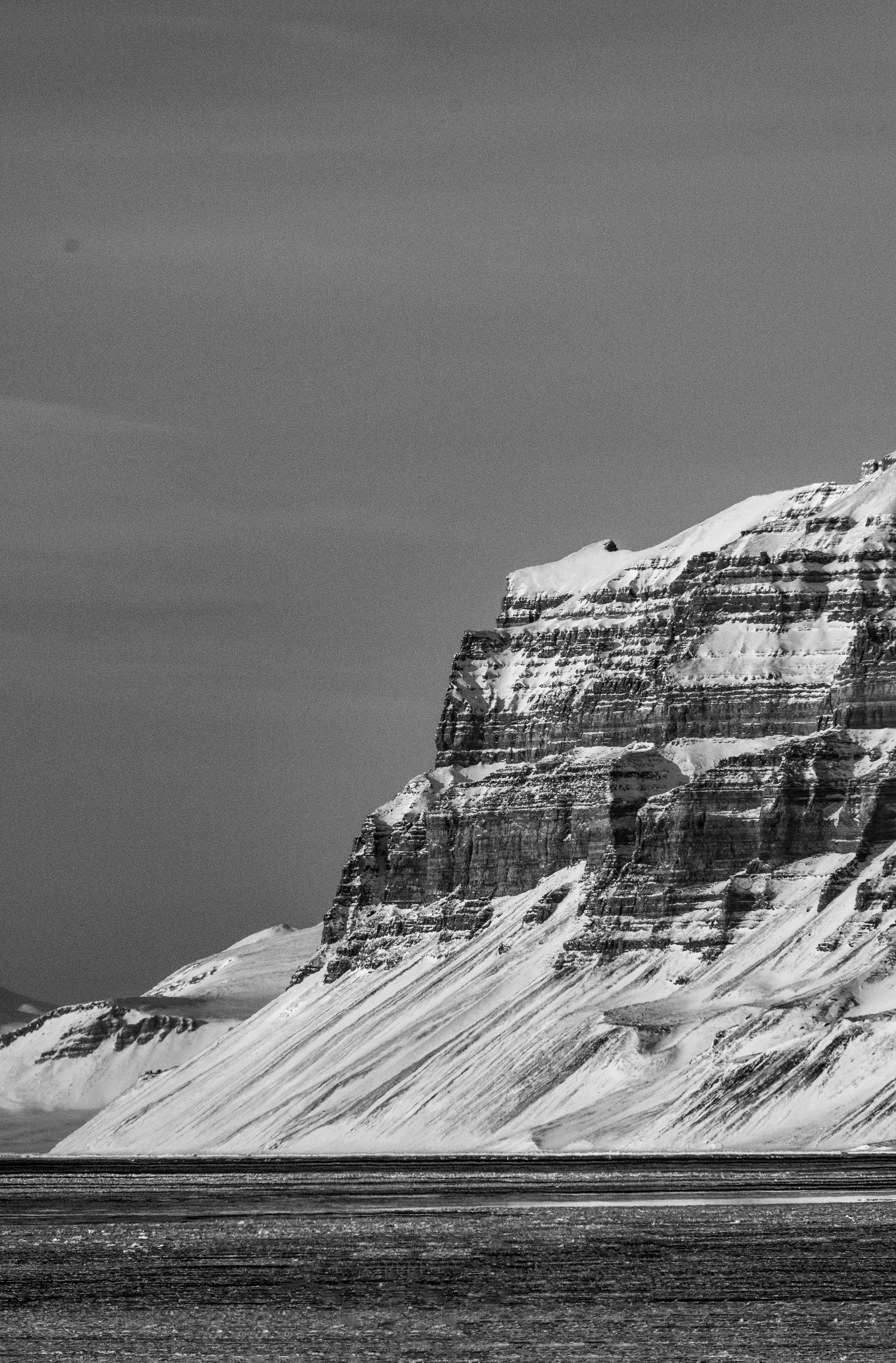 Svalbard, grey rocky glaciers, snow-dusted cliff face, 5K Phone Wallpaper