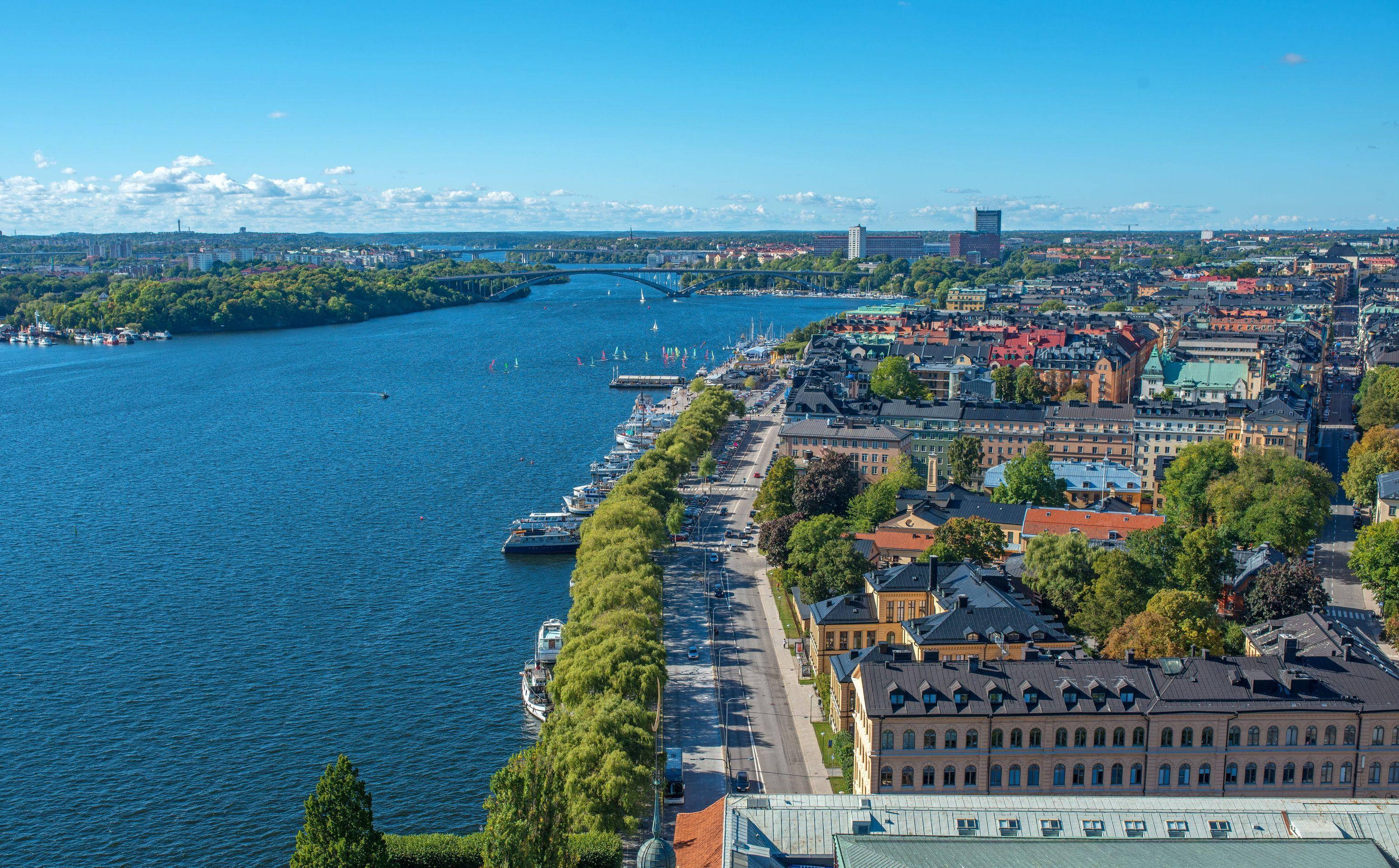 central Stockholm, wide blue river, lush green trees, 2K Desktop Wallpaper