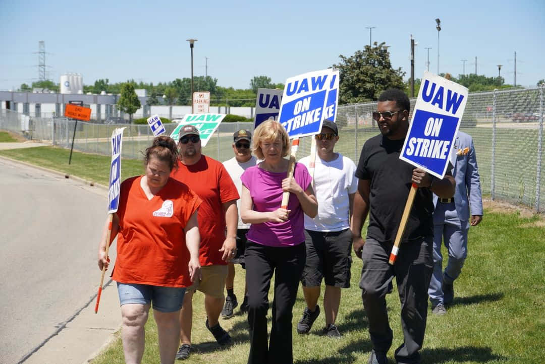 UAW workers, blue and white protest signs, sunlit roadside, SD Desktop Wallpaper