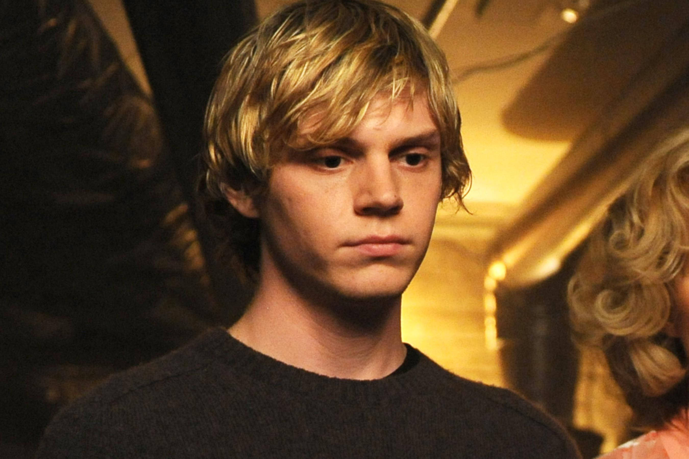 Tate Langdon, tousled blonde hair, warmly lit indoor setting, 2K Desktop Wallpaper