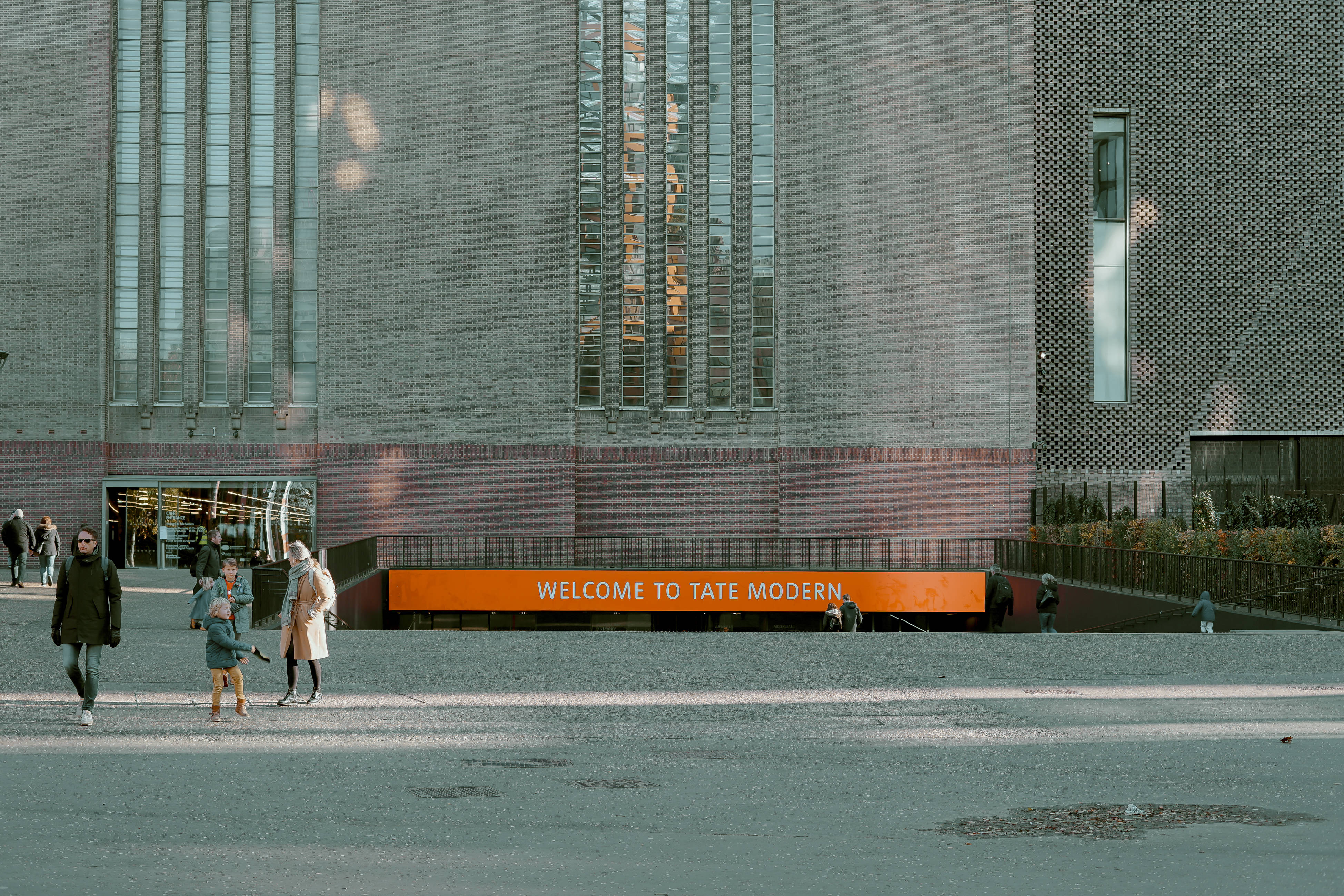 Tate Modern, grey brick facade, bold orange welcome sign, 4K Desktop Wallpaper