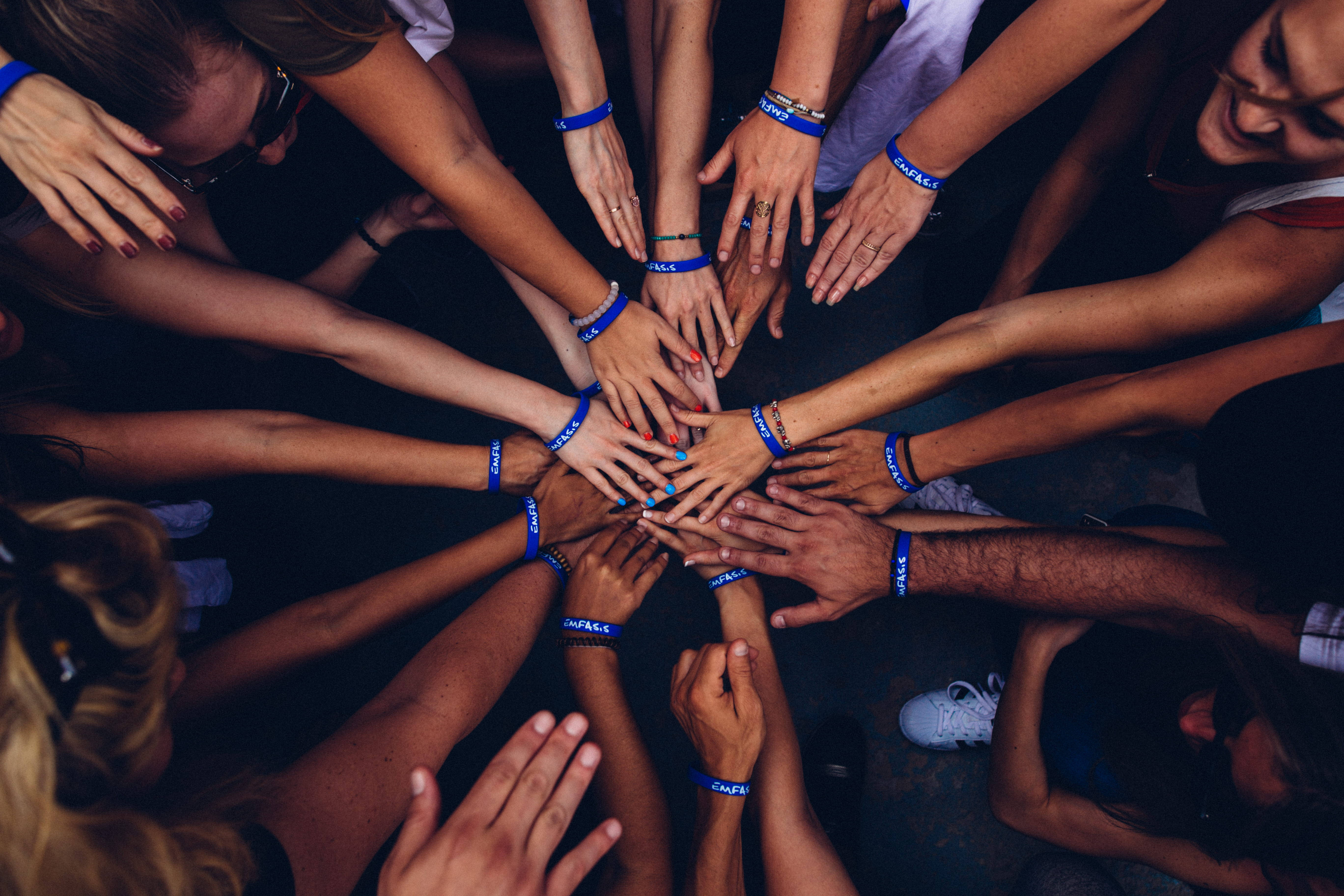 hands interlocked in a circle, blue wristbands, overhead view, 5K Desktop Wallpaper