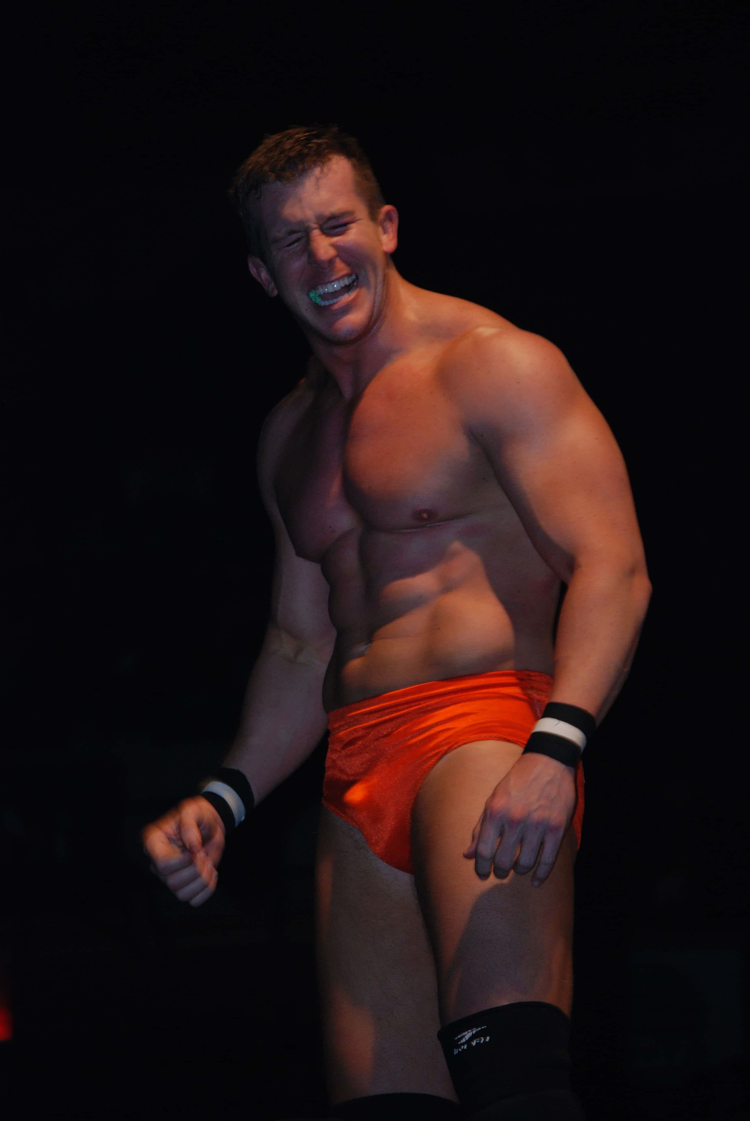 Ted Dibiase Jr., bright orange trunks, dramatic stage lighting, 4K Phone Wallpaper
