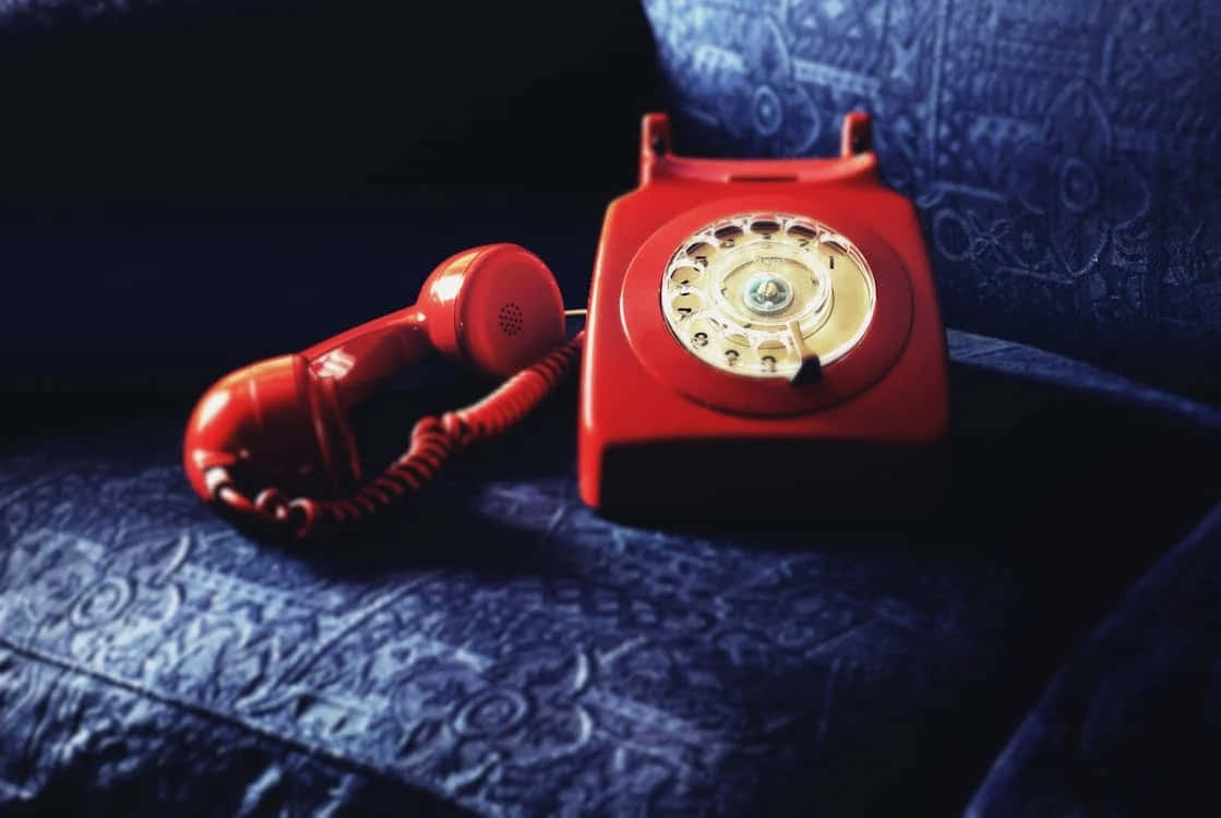 vintage red rotary phone, dark blue patterned fabric, dramatic lighting, SD Desktop Wallpaper