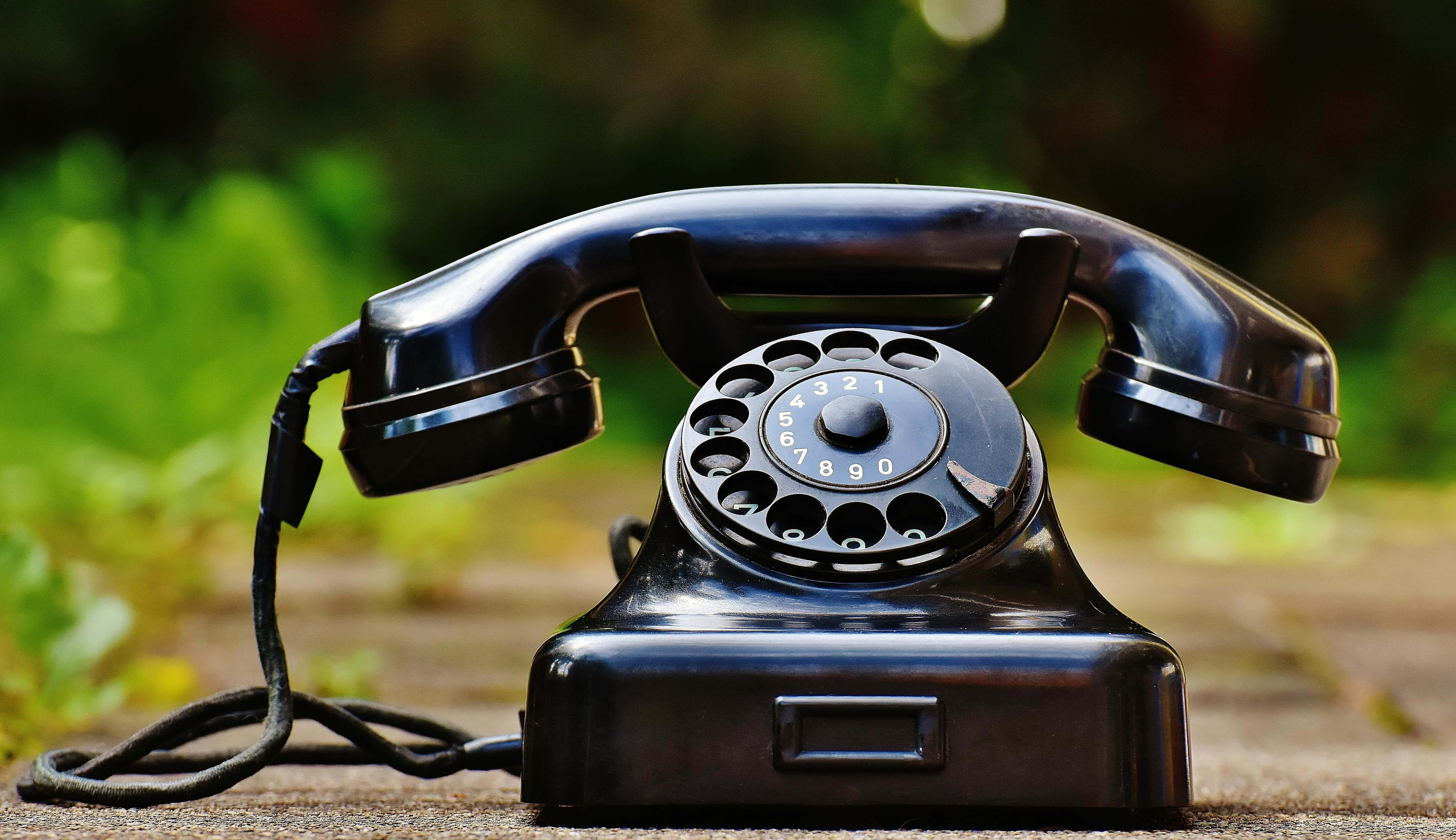vintage black rotary telephone, wooden surface, blurred green garden background, 5K Desktop Wallpaper