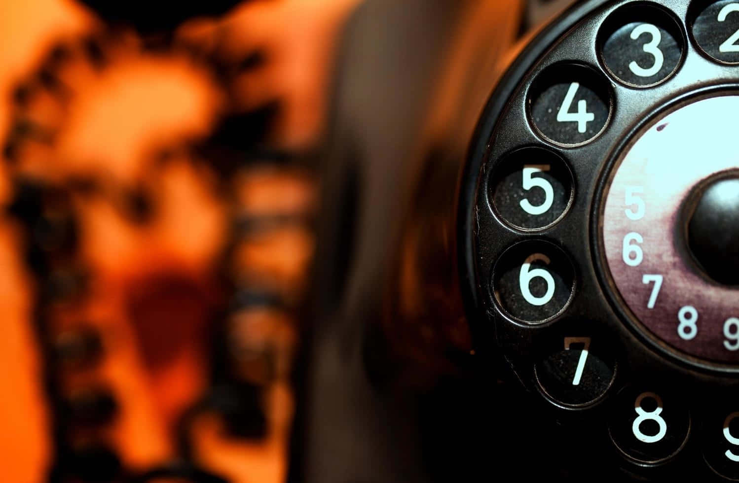 vintage rotary phone dial, glowing white numbers, warm orange blurred background, HD Desktop Wallpaper