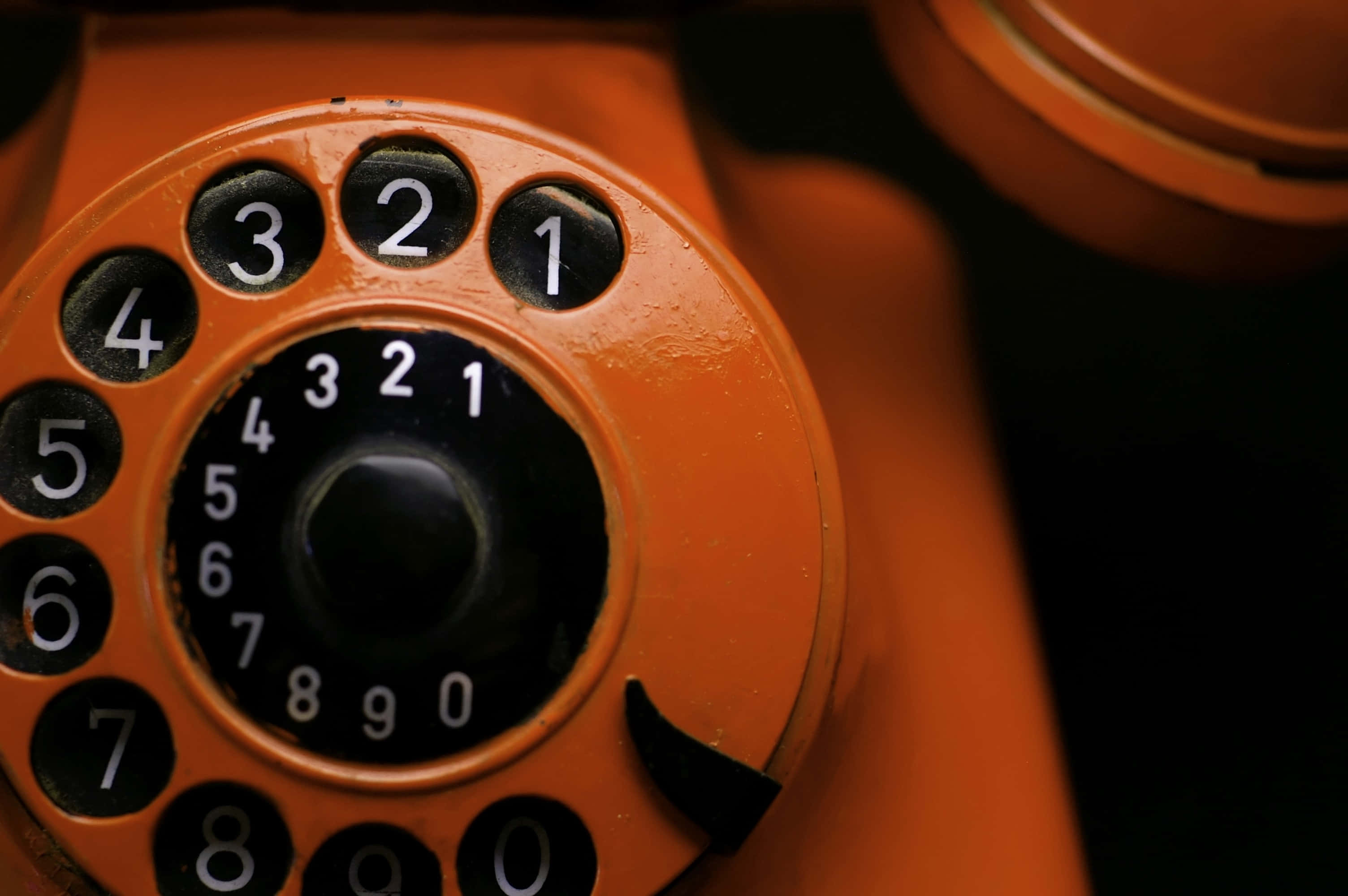 vintage orange rotary phone, worn numbers, dark background, 2K Desktop Wallpaper