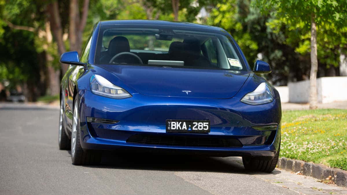 Tesla Model 3, glossy blue, tree-lined street, SD Desktop Wallpaper
