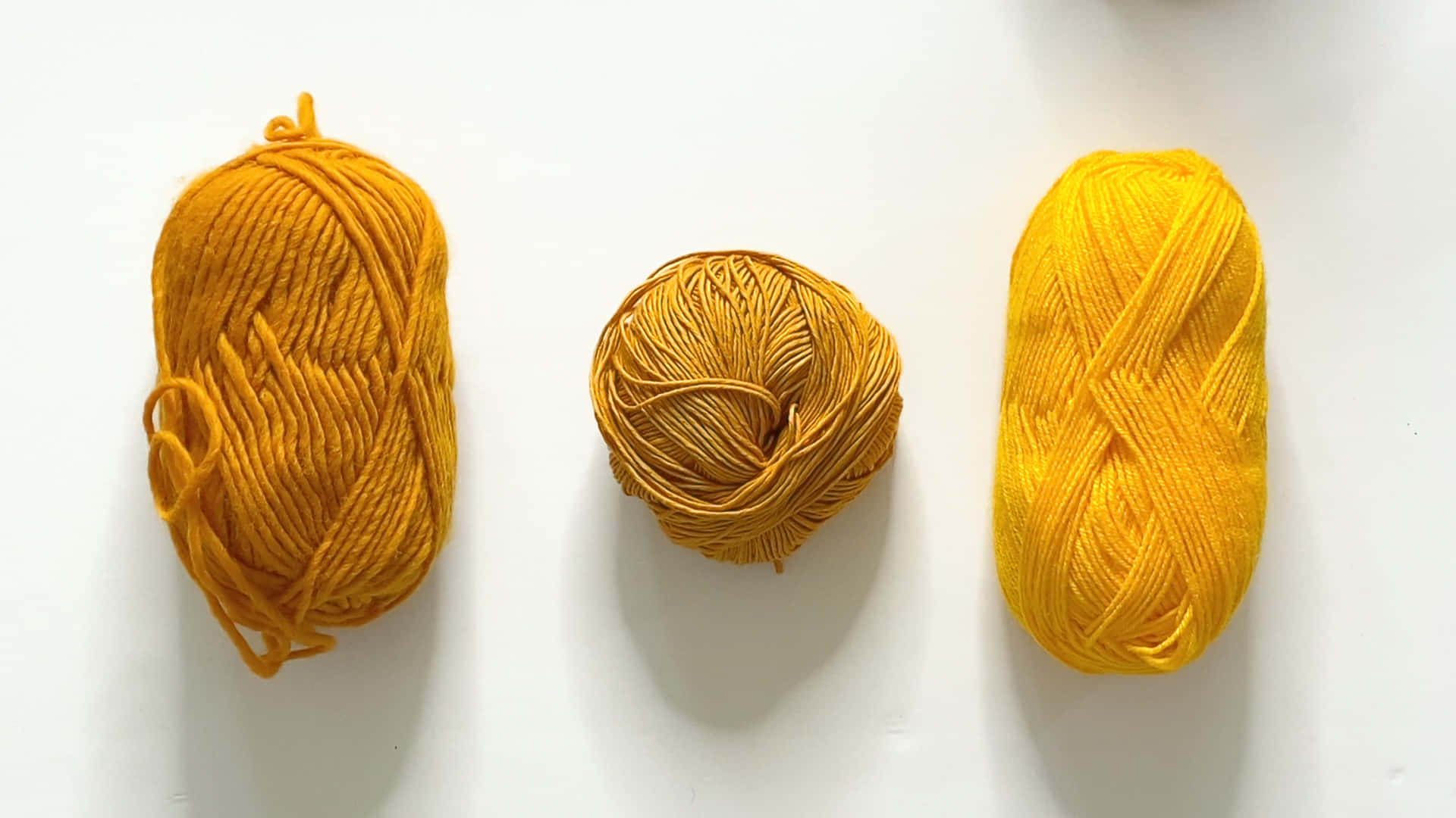 colorful yarn bundles, vibrant yellow yarn skeins, clean white surface, Full HD Desktop Wallpaper