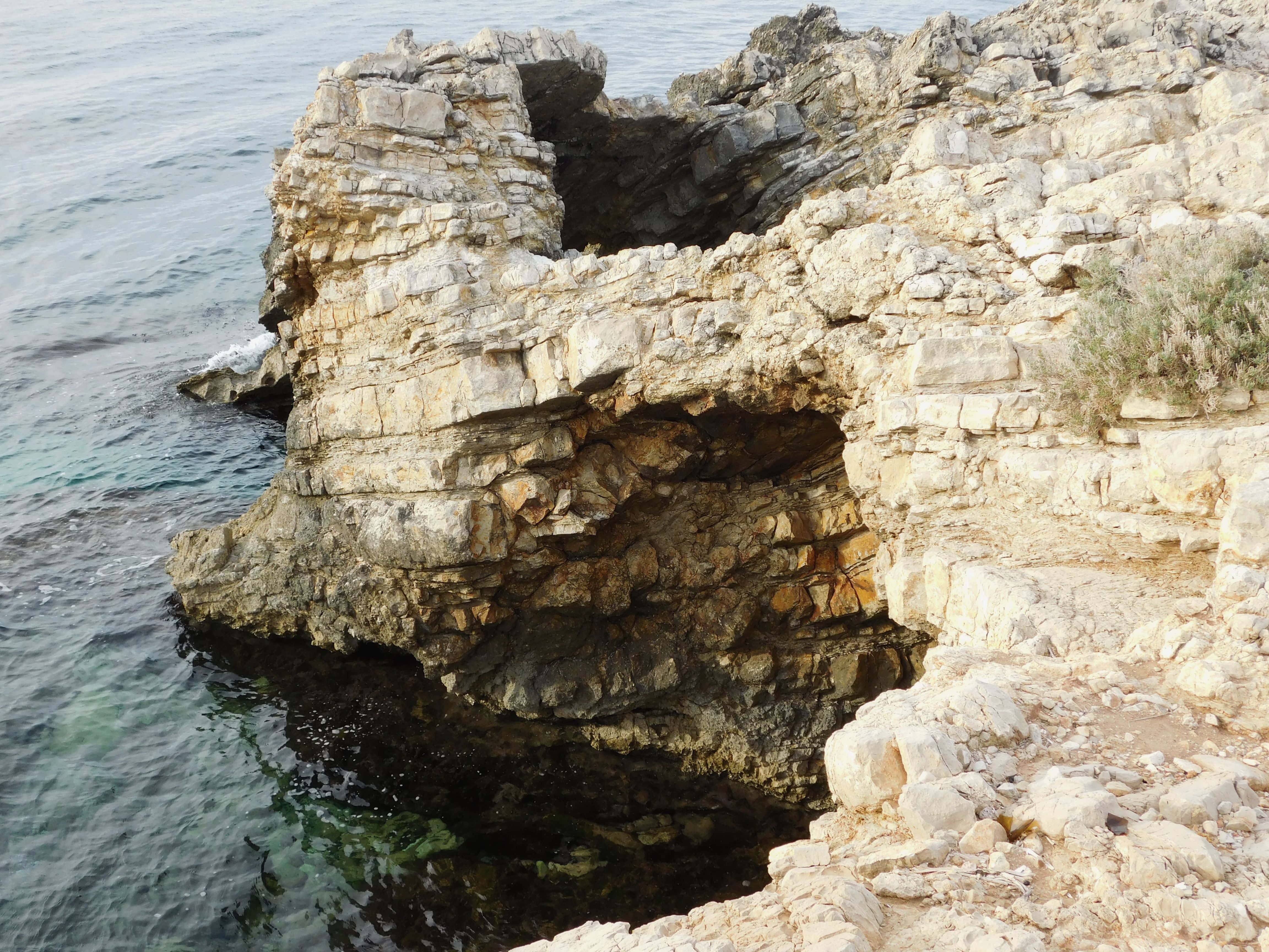 turquoise sea, sunlit layered rock formation, natural arches, 4K Desktop Wallpaper