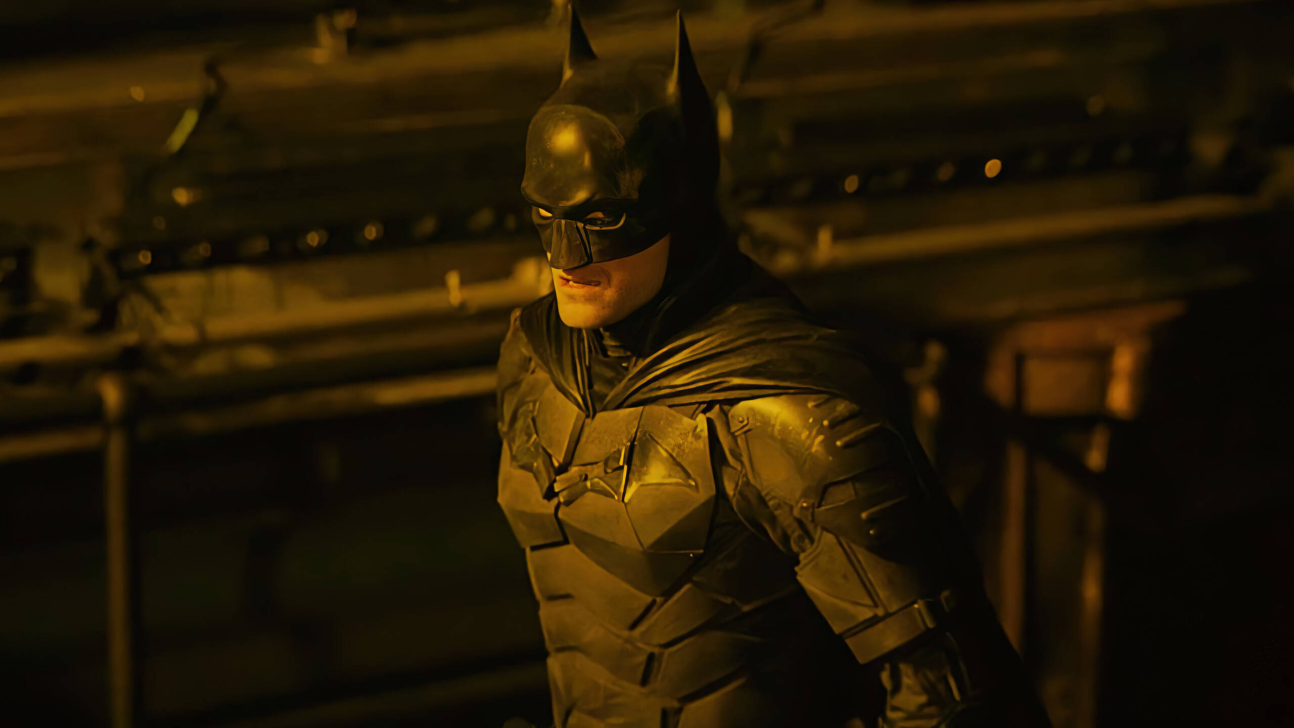 Batman, yellow light, dimly lit industrial setting, 2K Desktop Wallpaper
