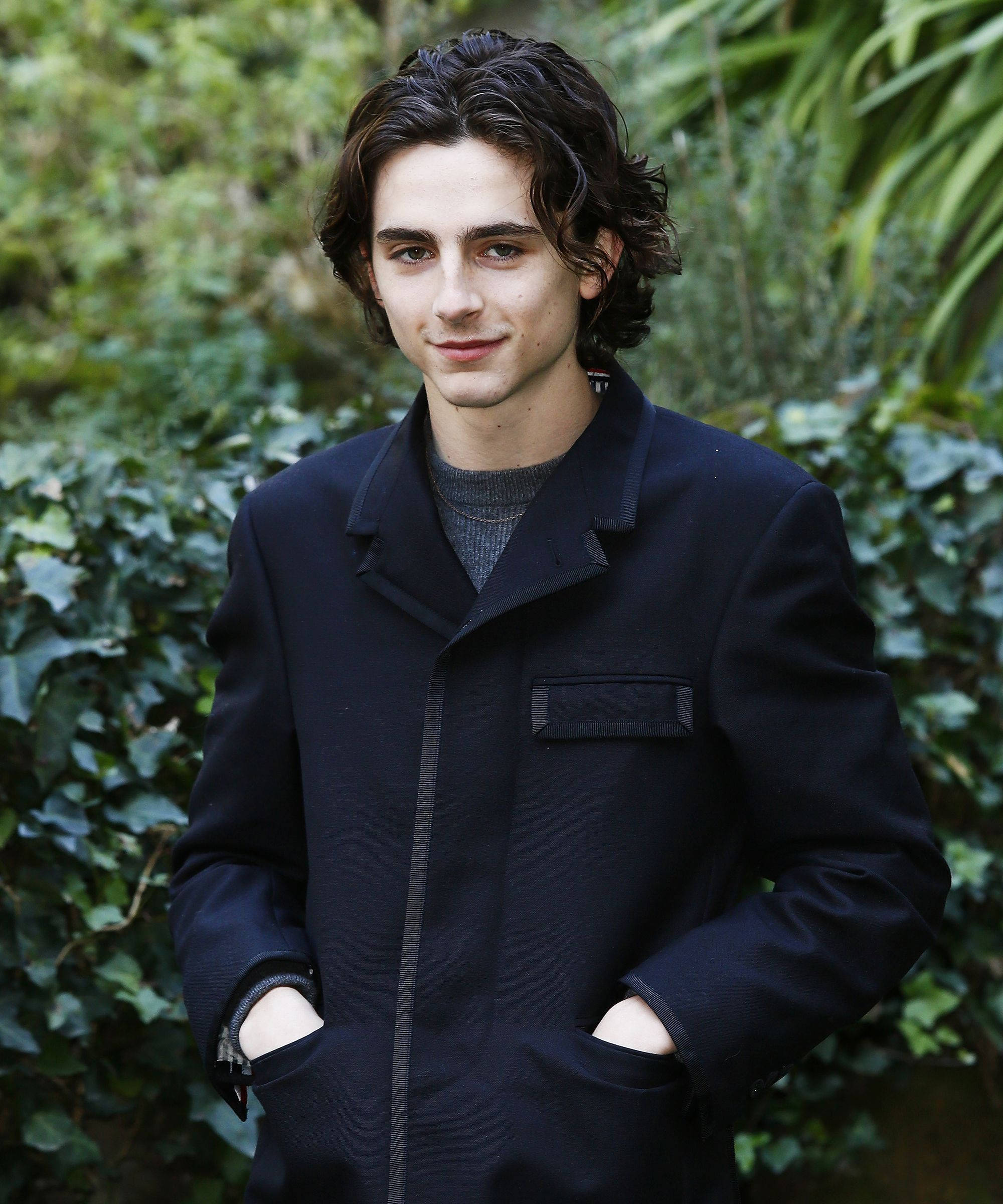 Timothée Chalamet, dark coat, lush green ivy backdrop, Full HD Phone Wallpaper