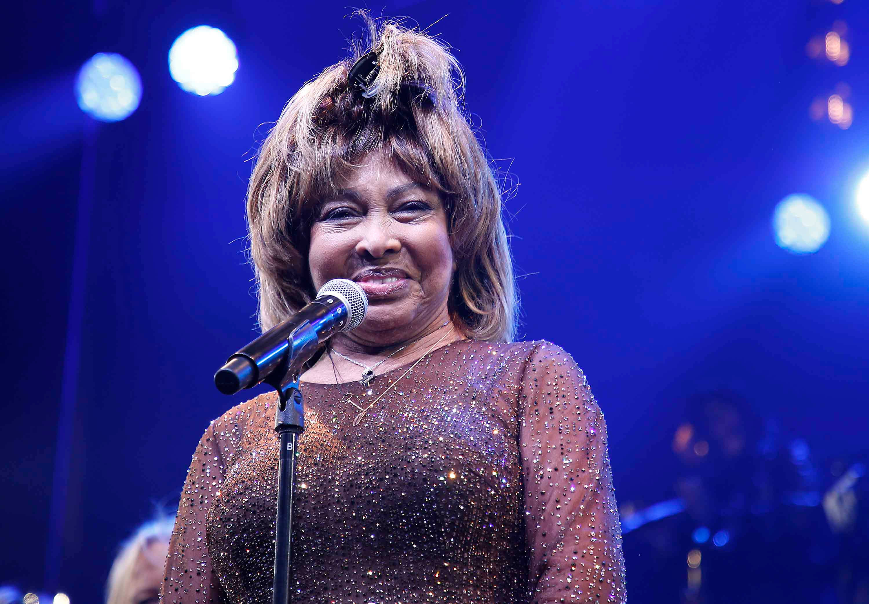 Tina Turner, glittering brown dress, blue stage lights, 2K Desktop Wallpaper