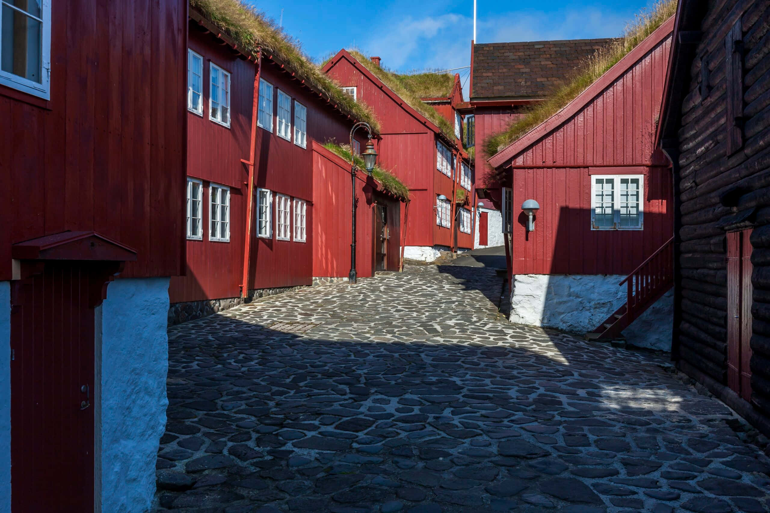 Tinganes, cobblestone alleyway, vibrant red wooden houses, 2K Desktop Wallpaper