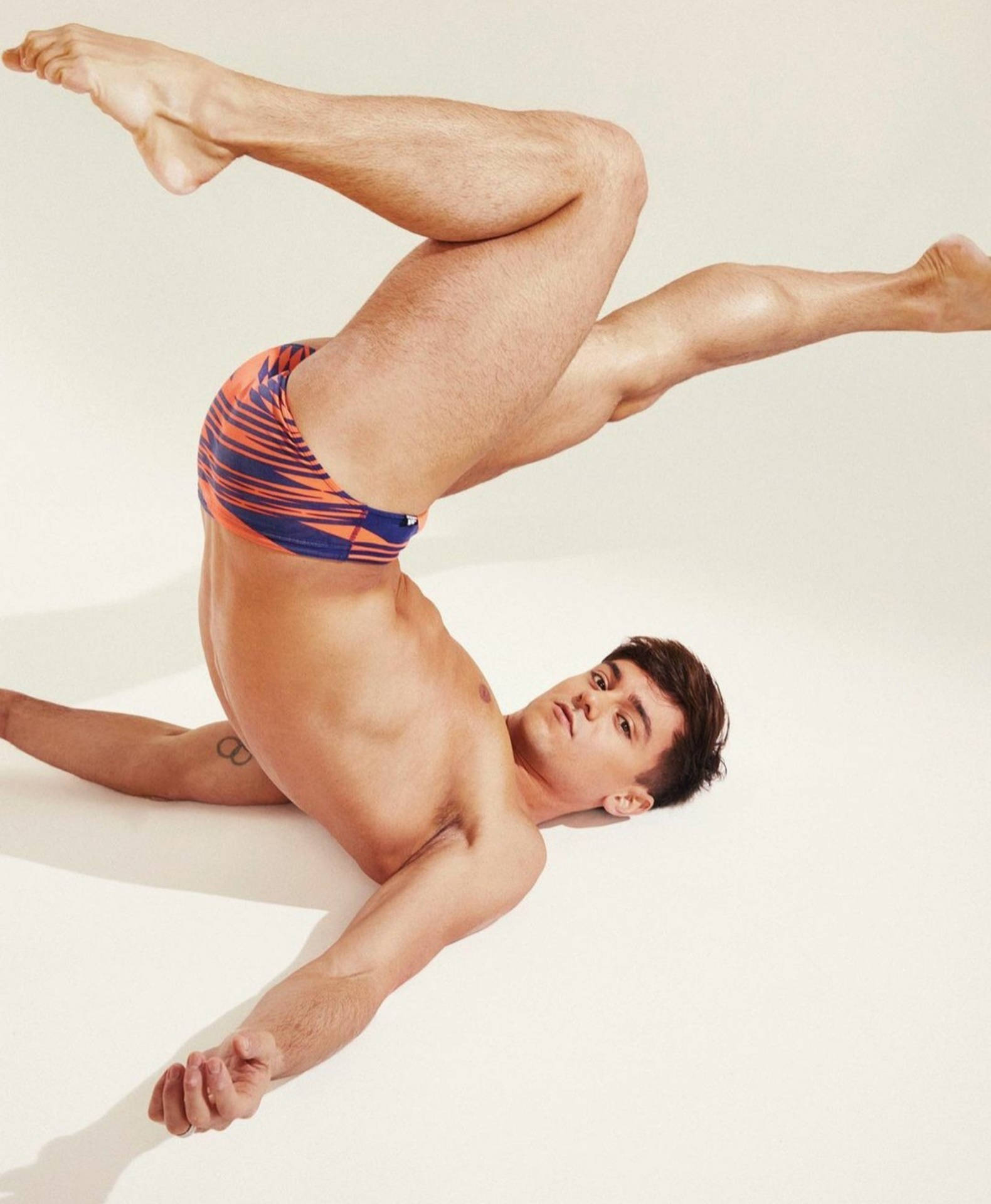 Tom Daley, orange and blue striped swim trunks, dynamic acrobatic pose, Full HD Phone Wallpaper