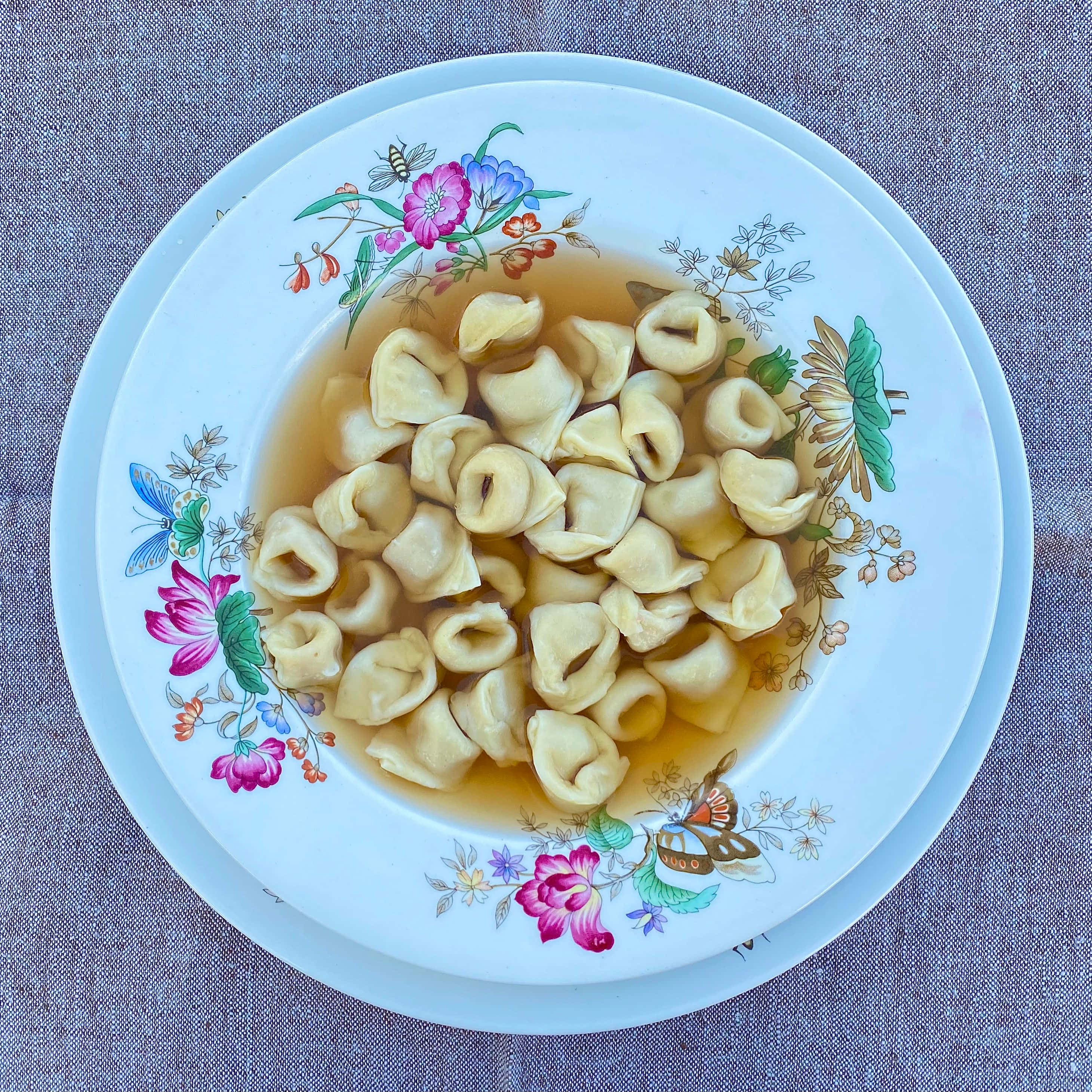 Tortellini In Brodo, floral-patterned plate, textured gray surface, 2K Desktop Wallpaper