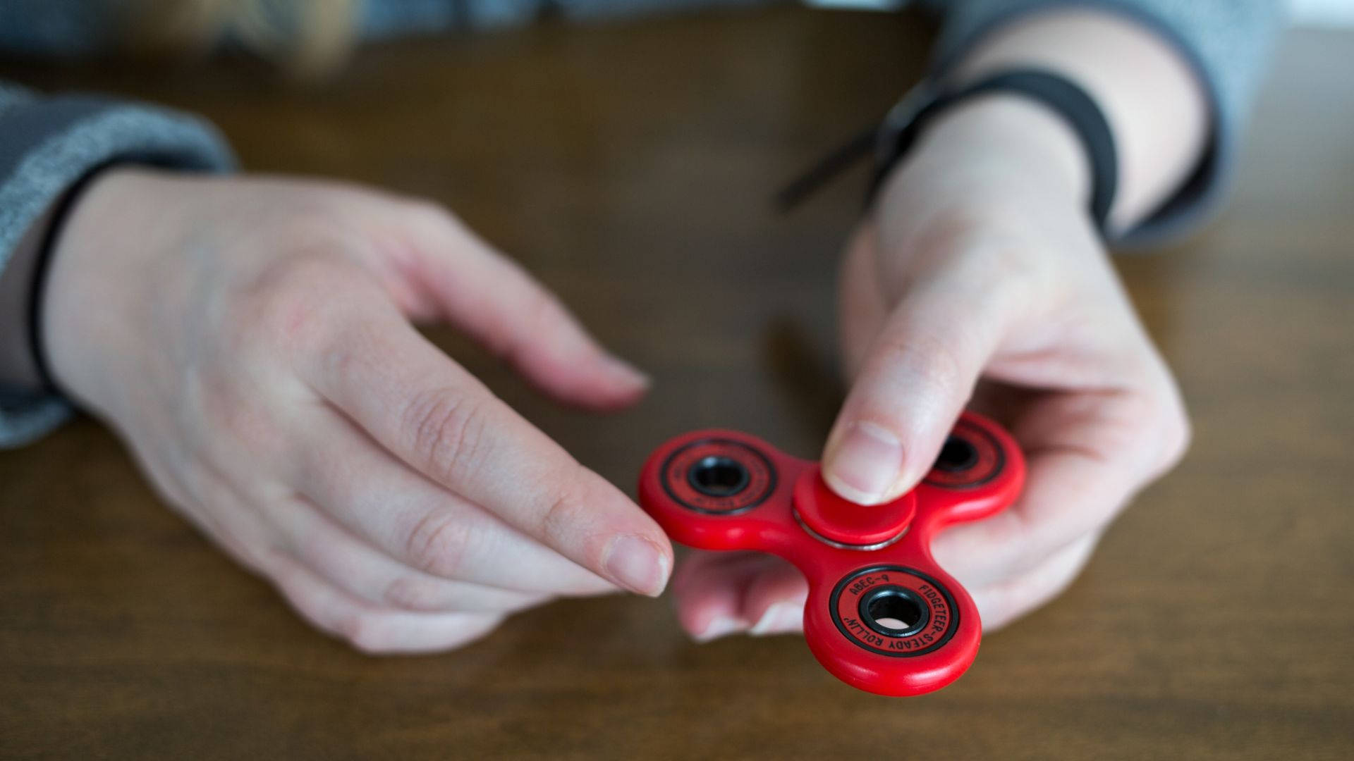 red fidget spinner, wooden table, hands, Full HD Desktop Wallpaper