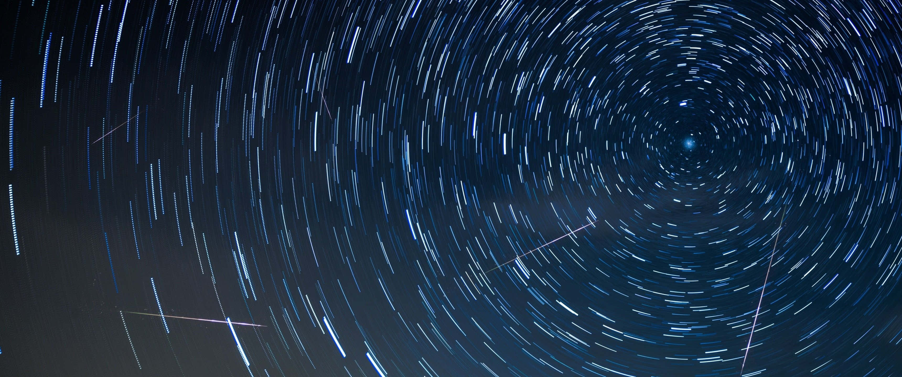 3440x1440, starry night sky, swirling blue-white star trails, 2K Desktop Wallpaper