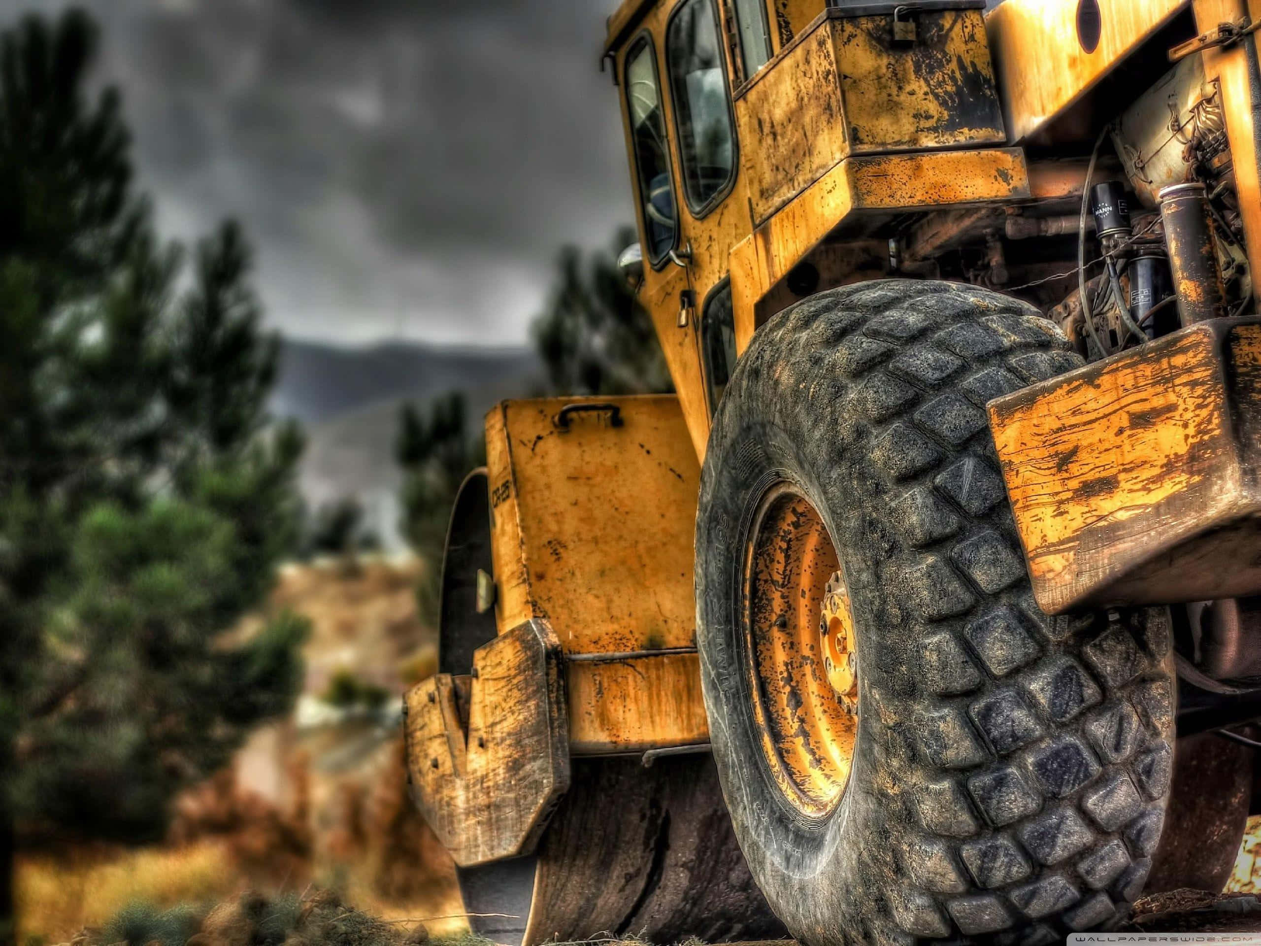 yellow construction vehicle, massive treaded tires, rugged outdoor scene, 2K Desktop Wallpaper