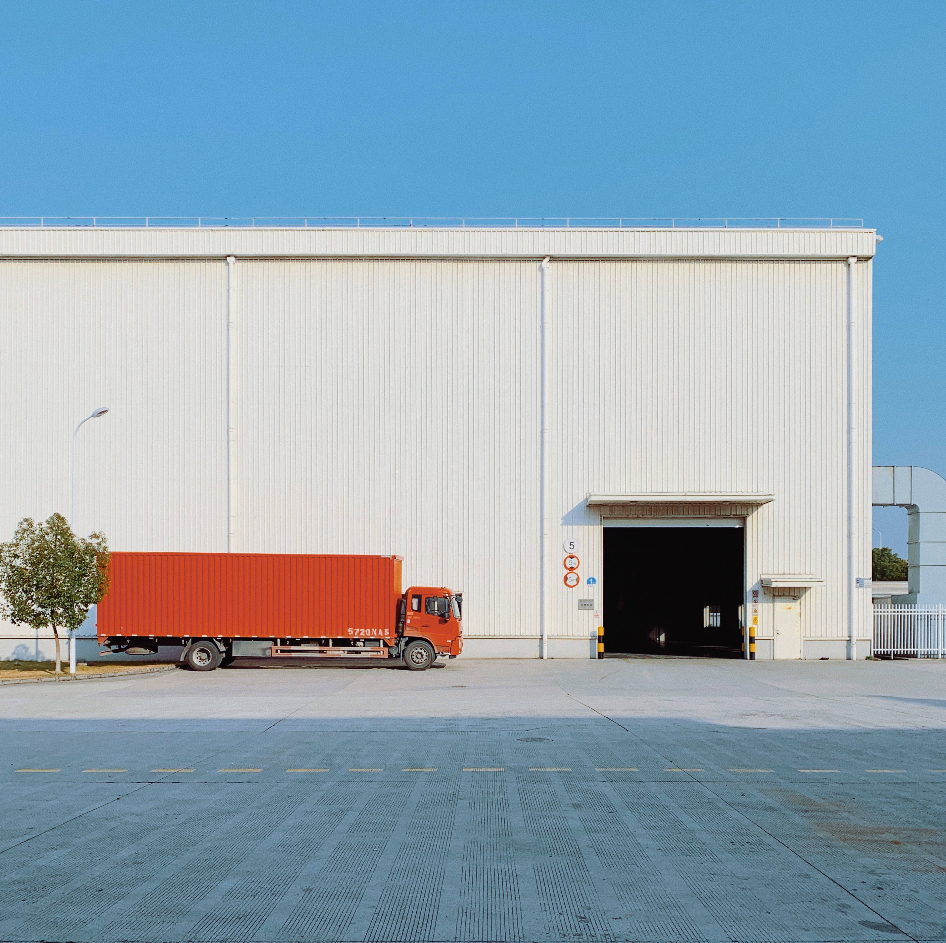 red freight truck, large white industrial warehouse, clear blue sky, 2K Desktop Wallpaper