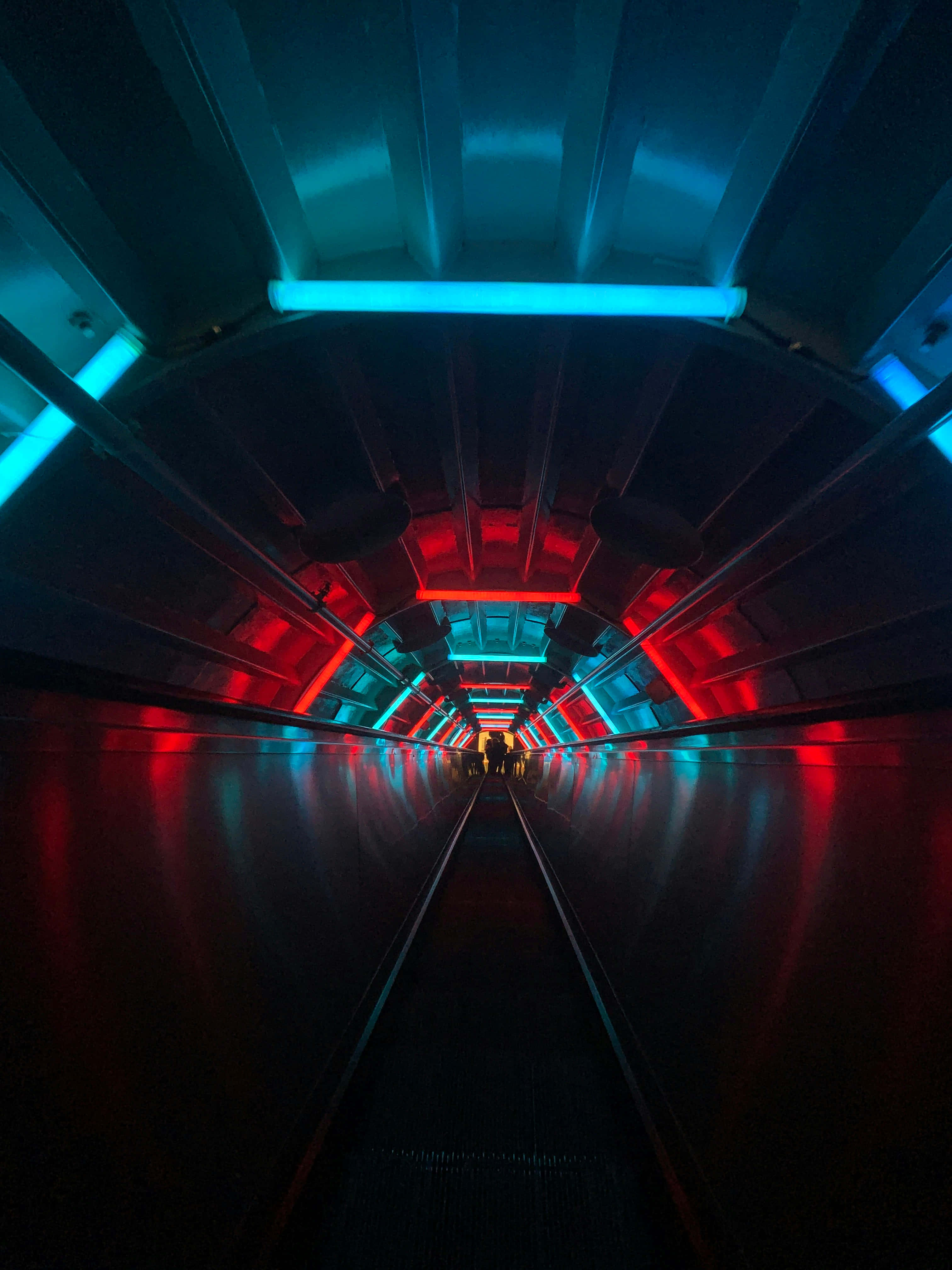 futuristic tunnel, glowing red and blue neon lights, silhouetted figures, 4K Phone Wallpaper