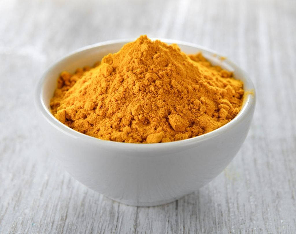 turmeric powder, white ceramic bowl, weathered light gray wooden surface, SD Desktop Wallpaper