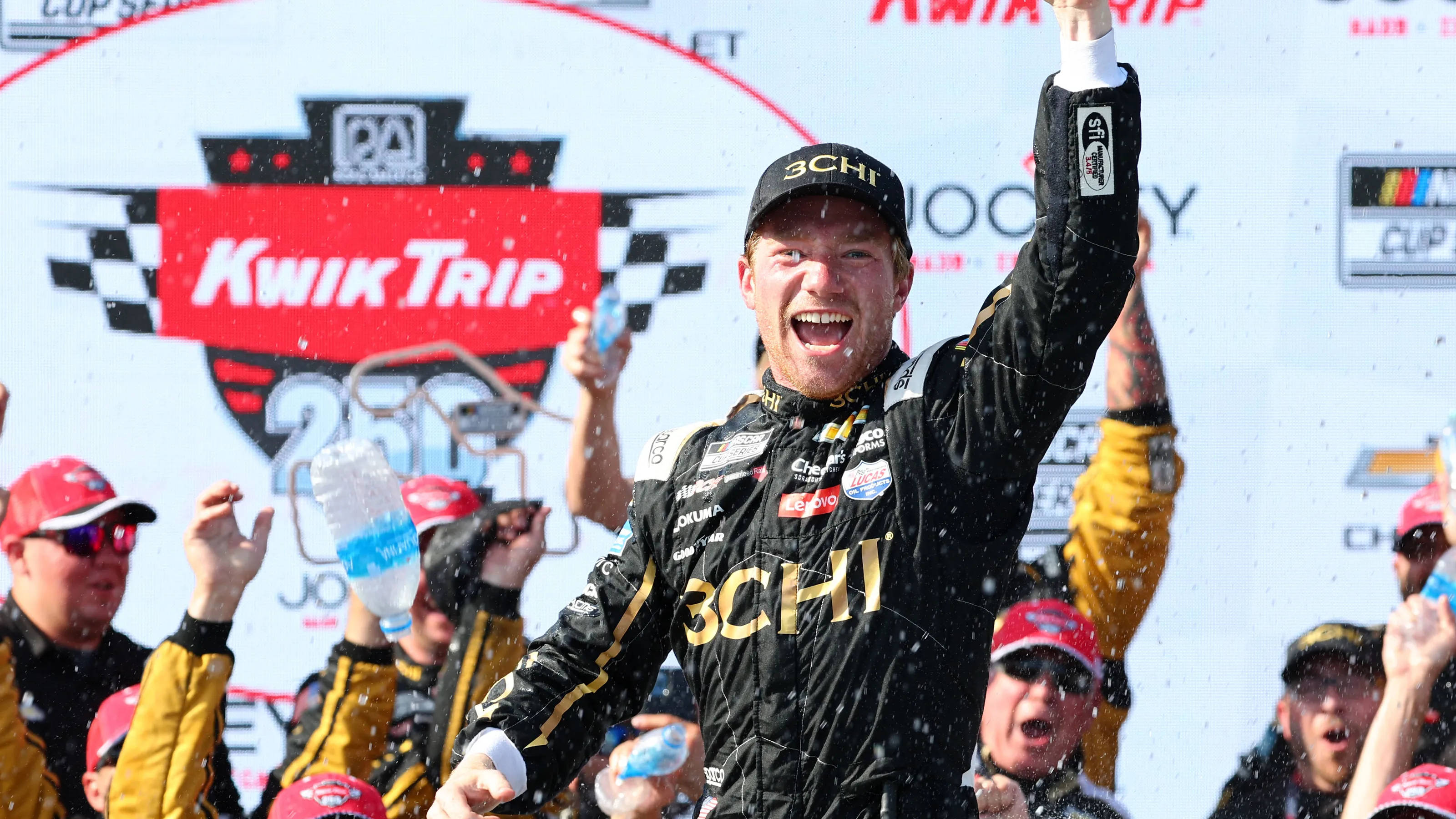 Tyler Reddick, black and gold racing suit, podium, 2K Desktop Wallpaper
