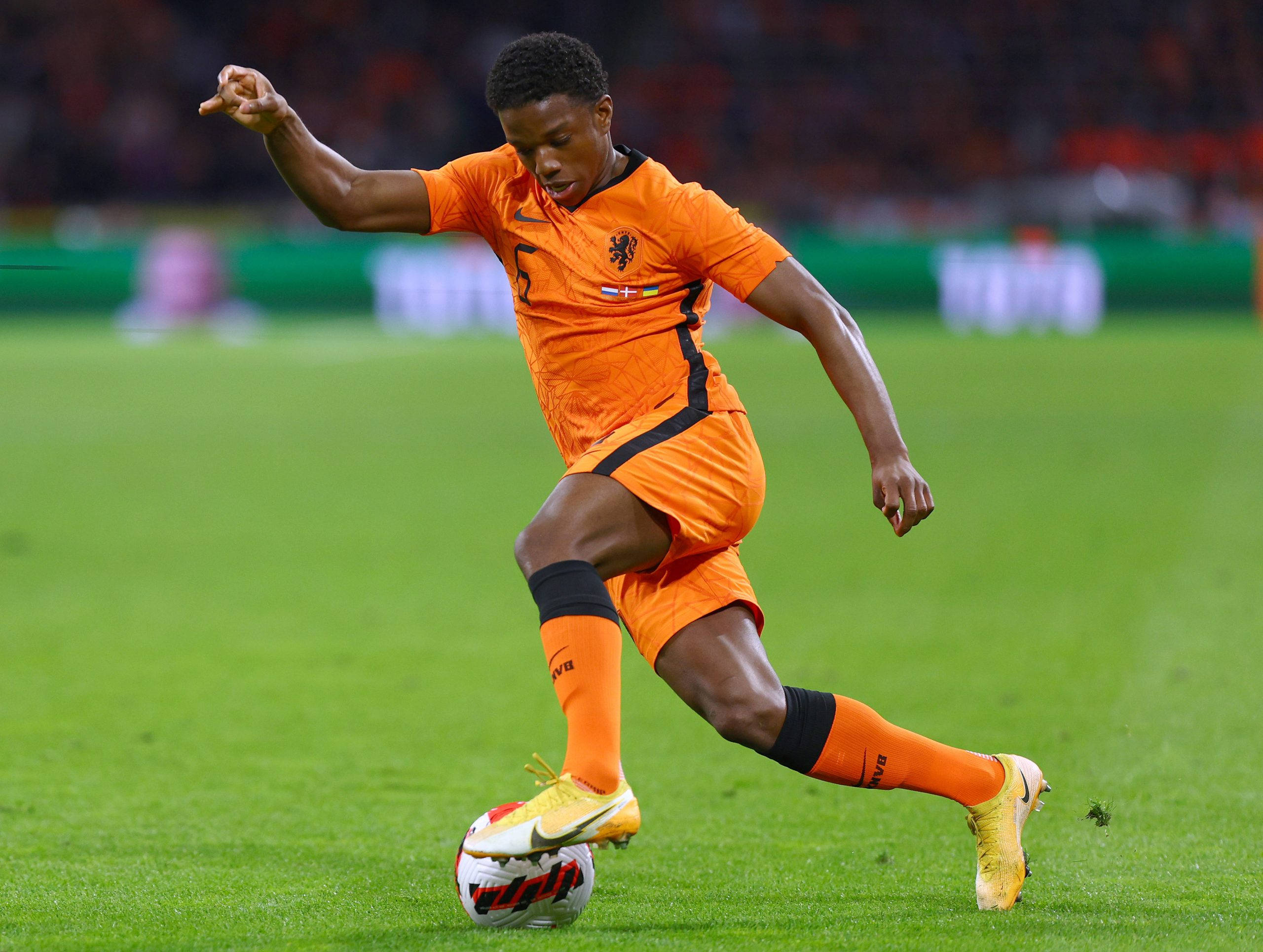 Tyrell Malacia, orange kit, lush green pitch, 2K Desktop Wallpaper