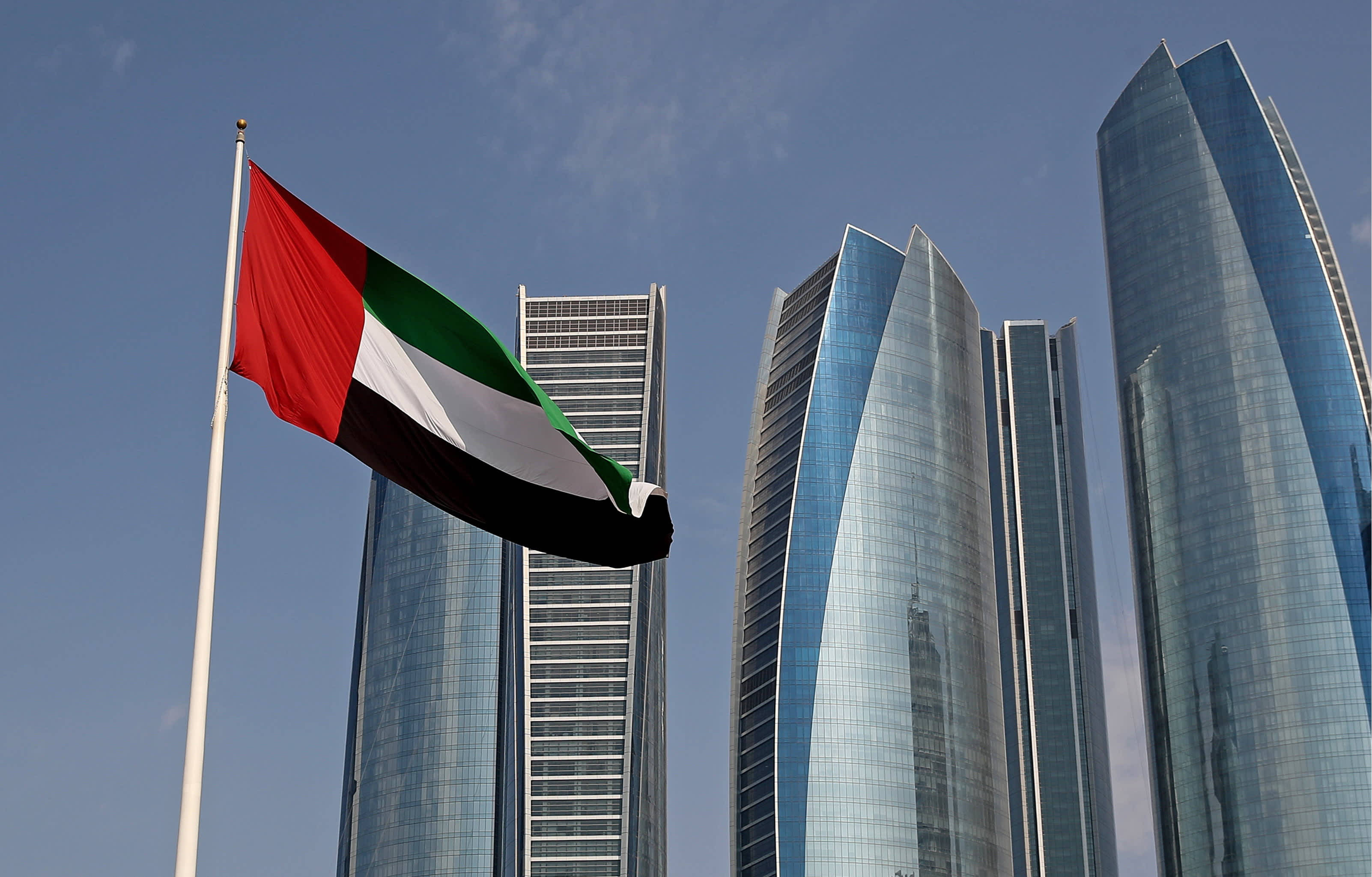 UAE flag, clear blue sky, sleek modern skyscrapers, 2K Desktop Wallpaper