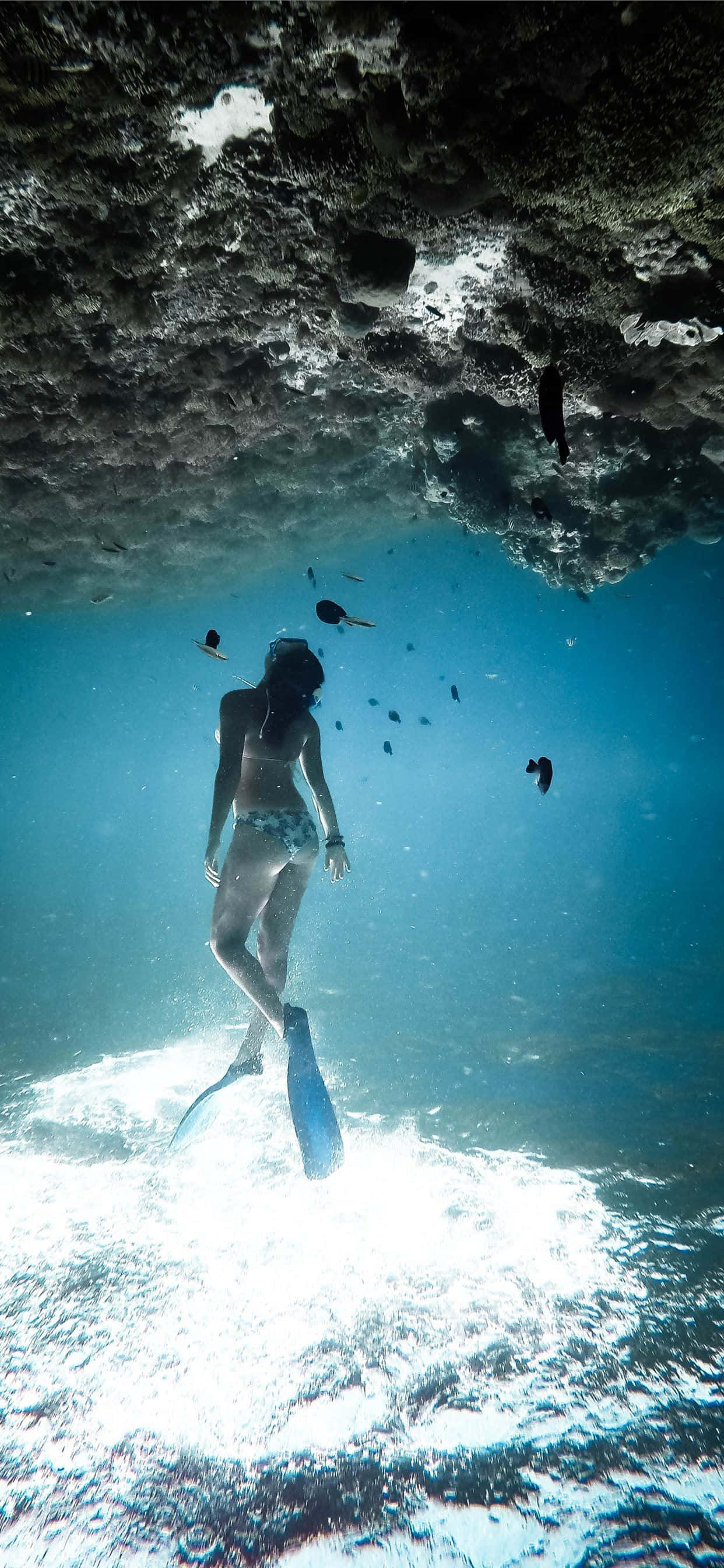 Underwater iPhone, snorkeler, sunlit sea cave, 2K Phone Wallpaper