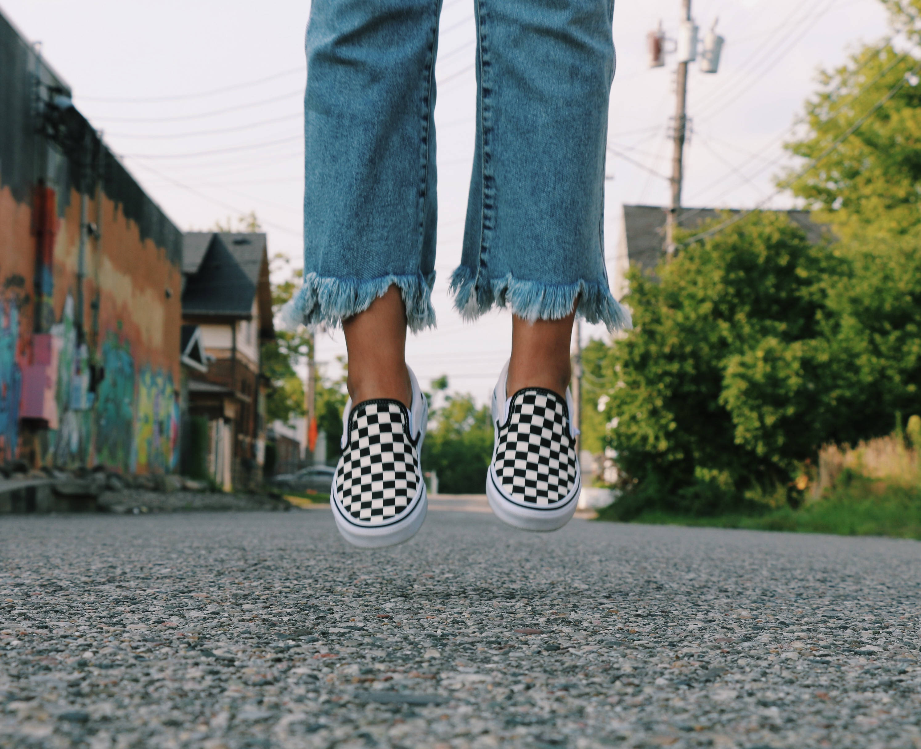 Vans, checkered slip-on shoes, graffiti-covered urban street, 2K Desktop Wallpaper