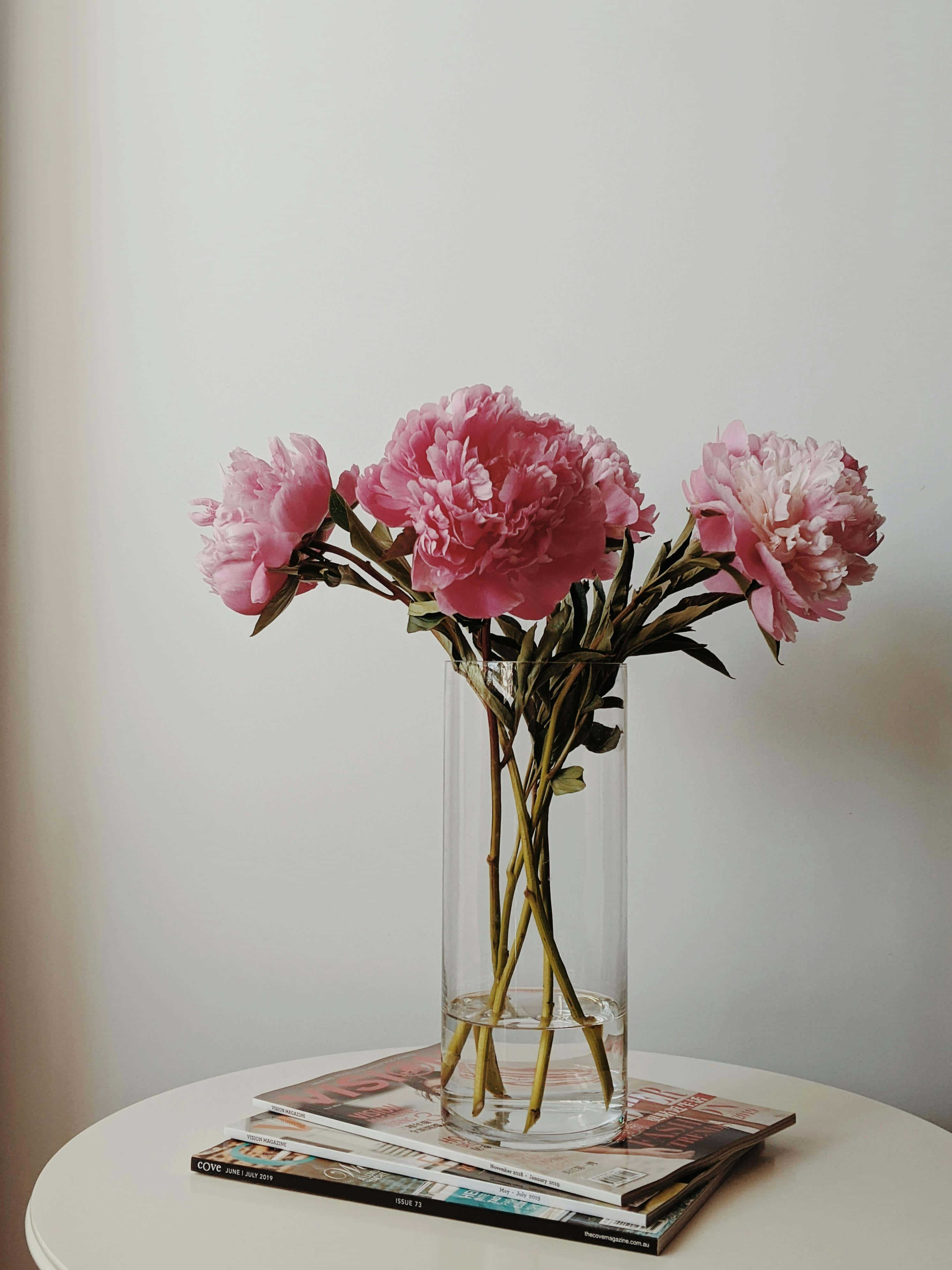 pink peonies, clear glass vase, stacked magazines, 4K Phone Wallpaper