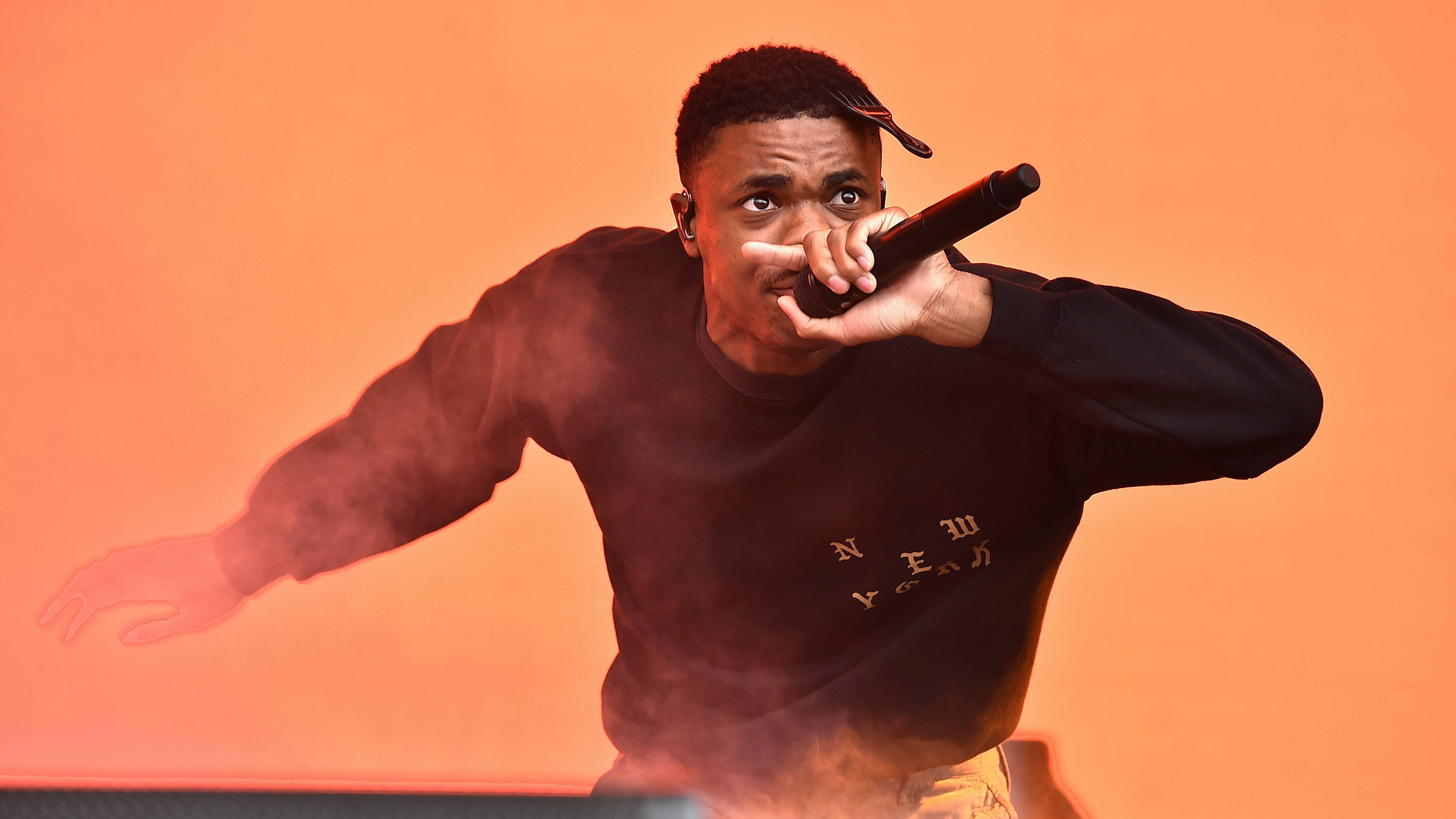 Vince Staples, glowing orange backdrop, smoke swirling, 2K Desktop Wallpaper