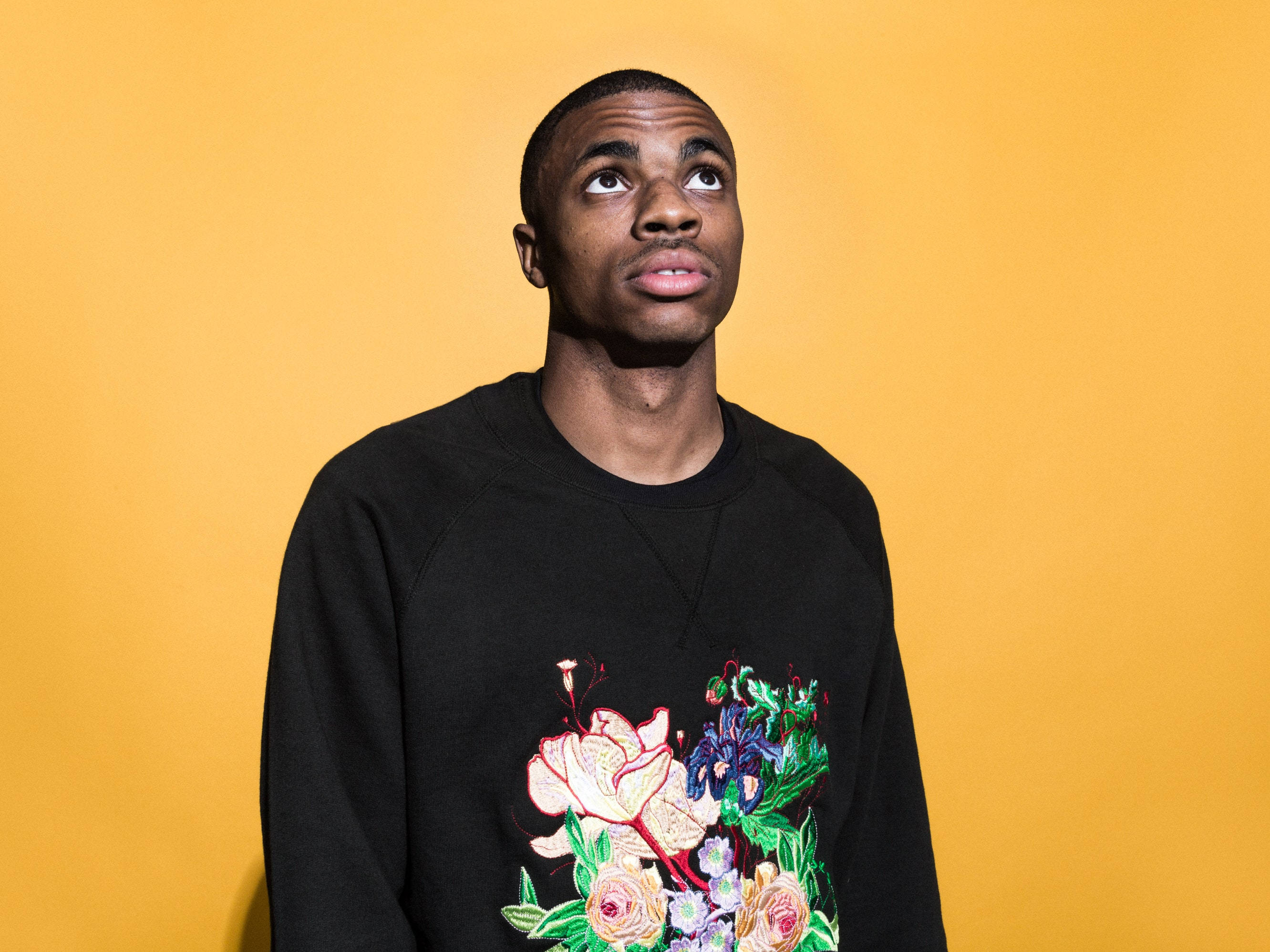 Vince Staples, black floral sweatshirt, warm yellow background, 2K Desktop Wallpaper