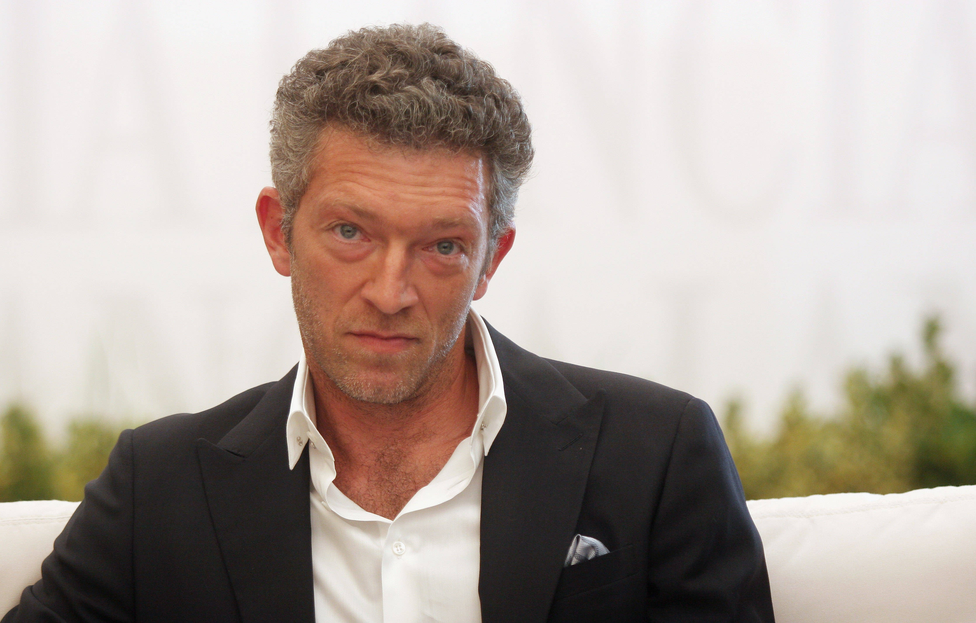 Vincent Cassel, black suit, white couch, 2K Desktop Wallpaper