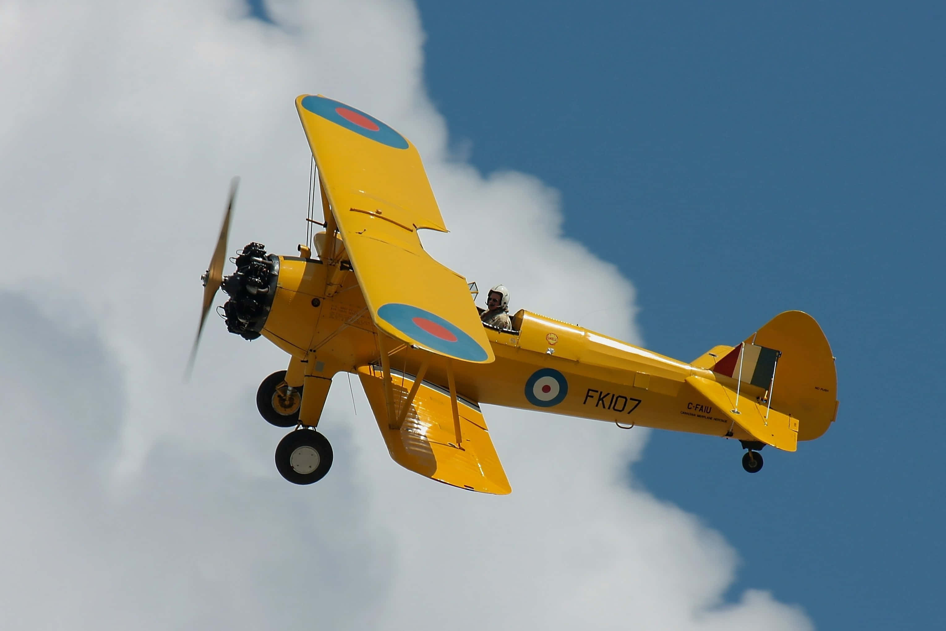 bright yellow biplane, roundel markings, partly cloudy blue sky, 2K Desktop Wallpaper