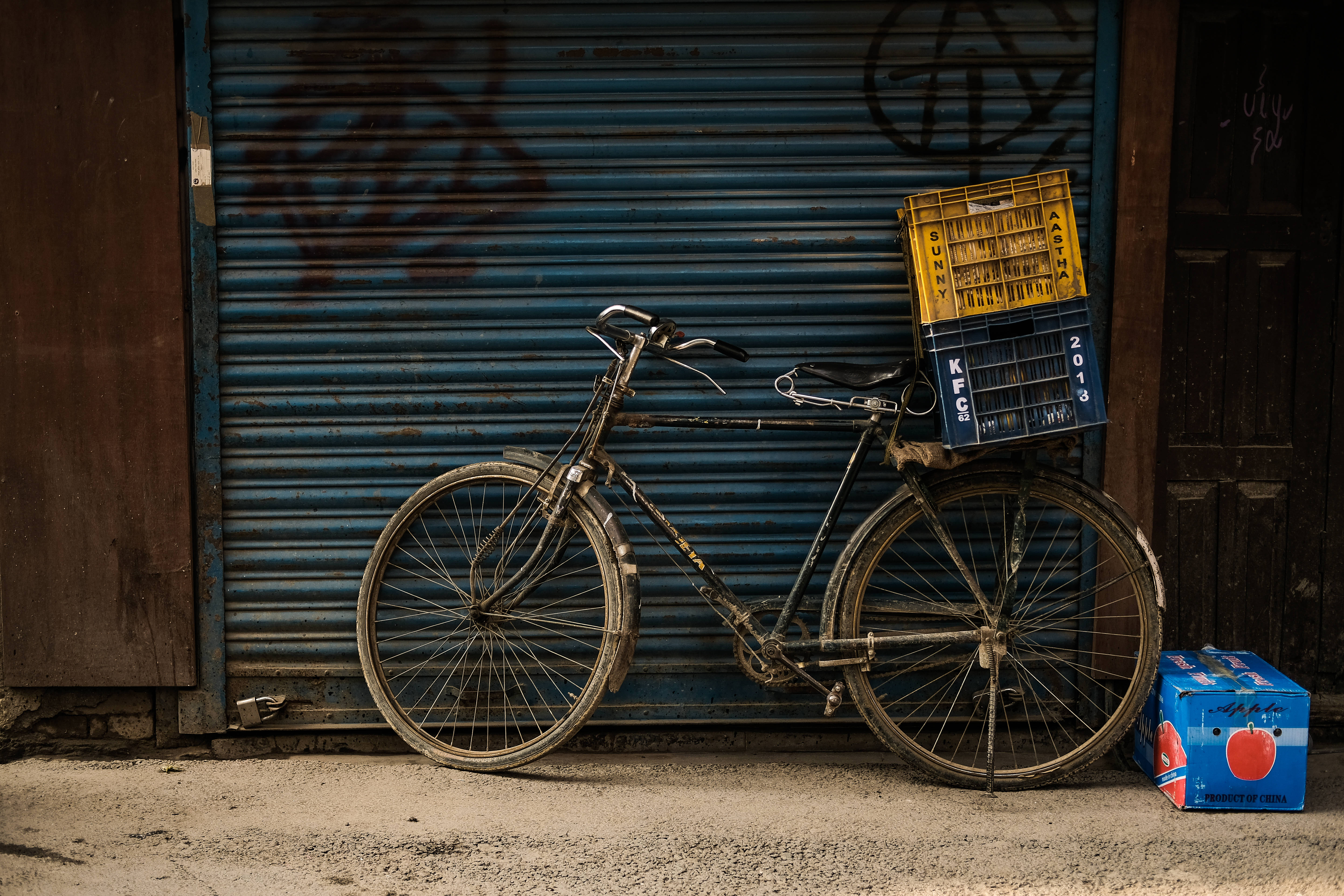 vintage bike, yellow and blue crate, graffiti-scarred blue metal shutter, 5K Desktop Wallpaper