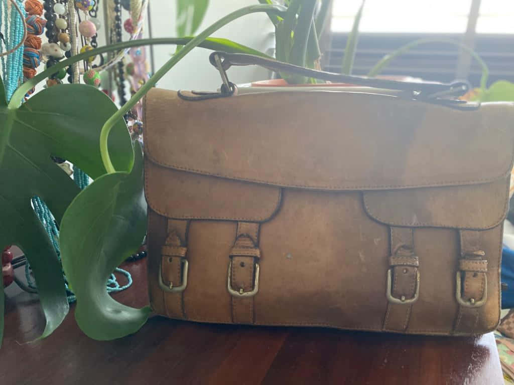 tan leather satchel, brass buckles, wooden table, SD Desktop Wallpaper
