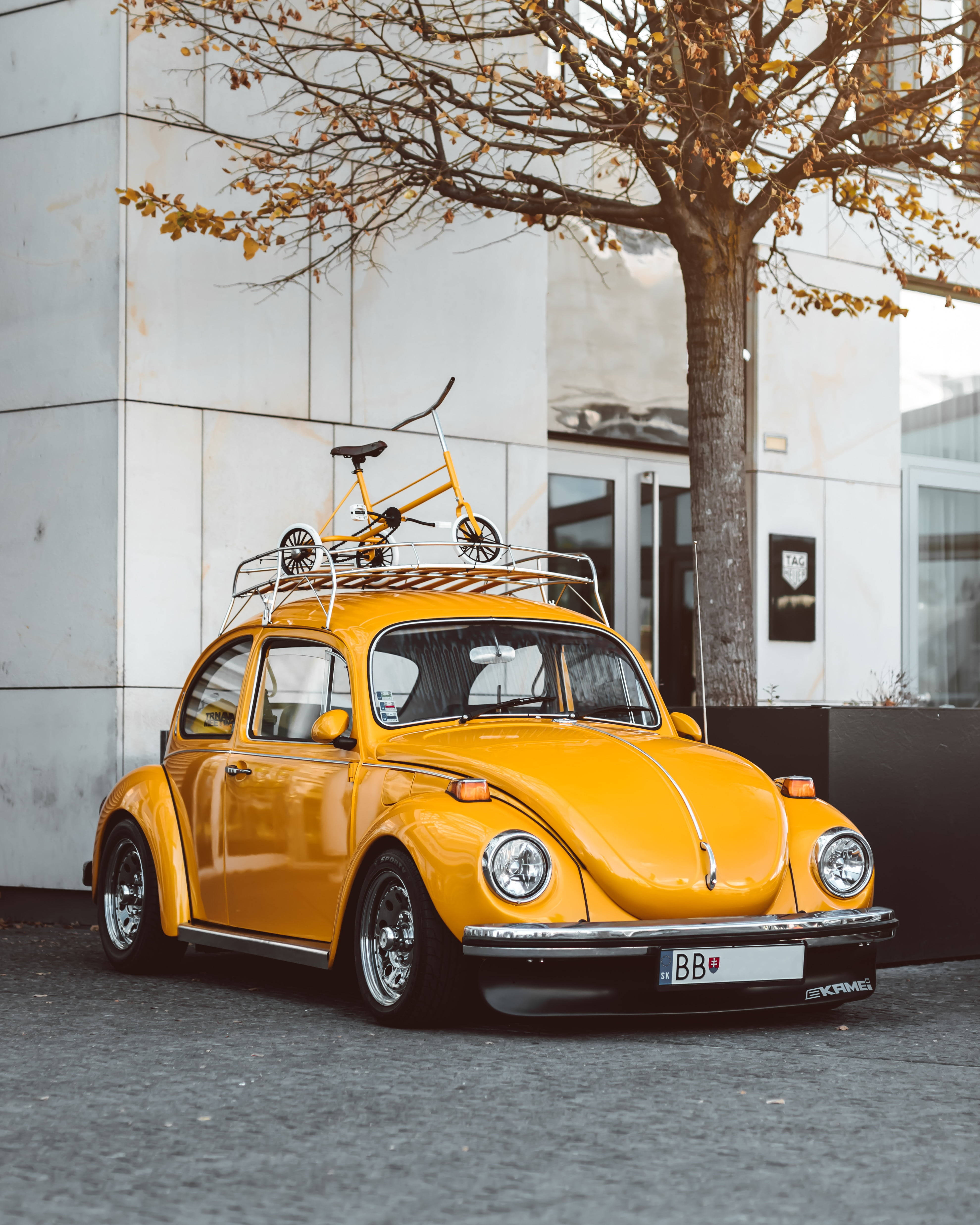vintage Volkswagen Beetle, vibrant yellow, bike on roof rack, 4K Phone Wallpaper