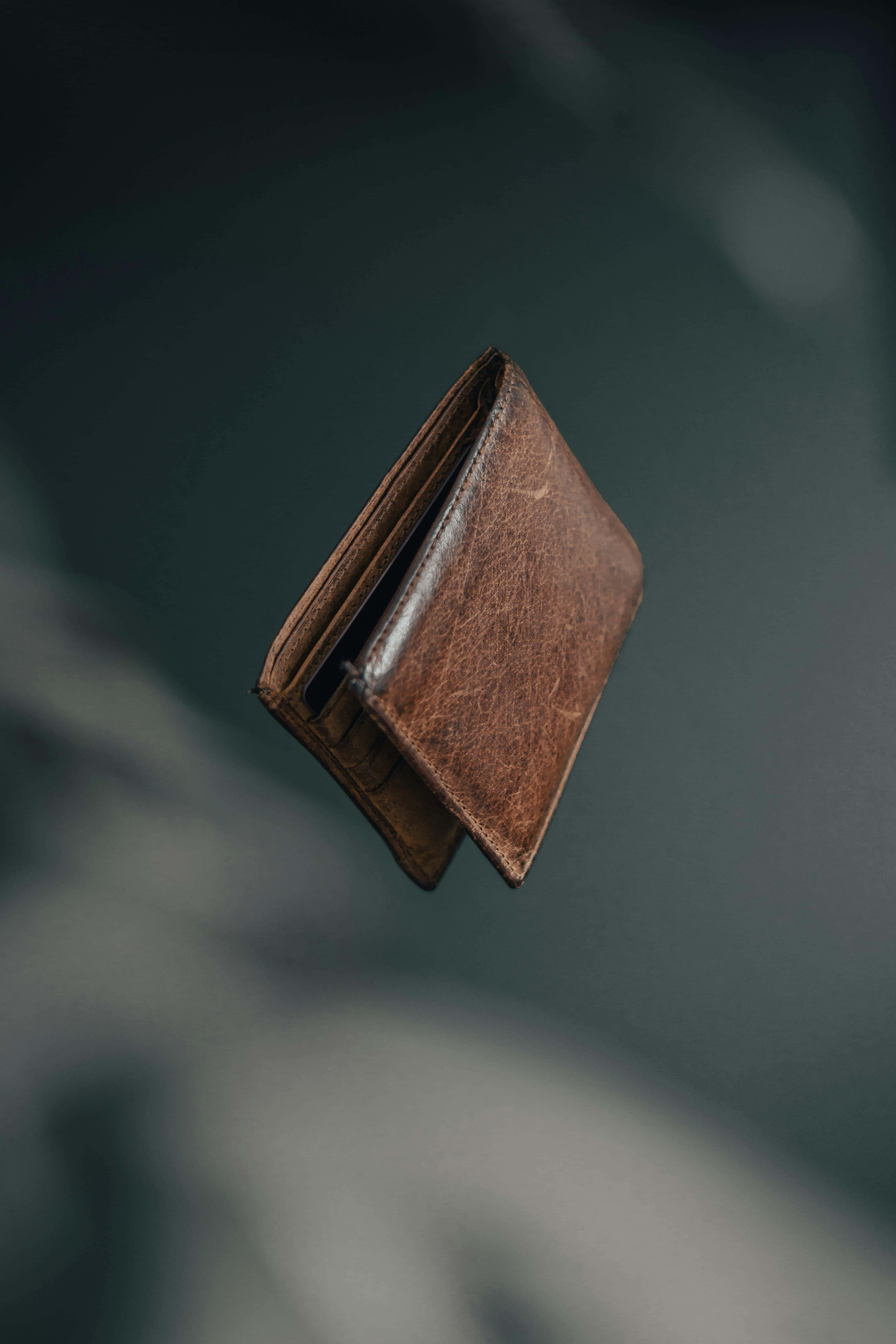 levitating, brown leather wallet, dark blurred background, 5K Phone Wallpaper