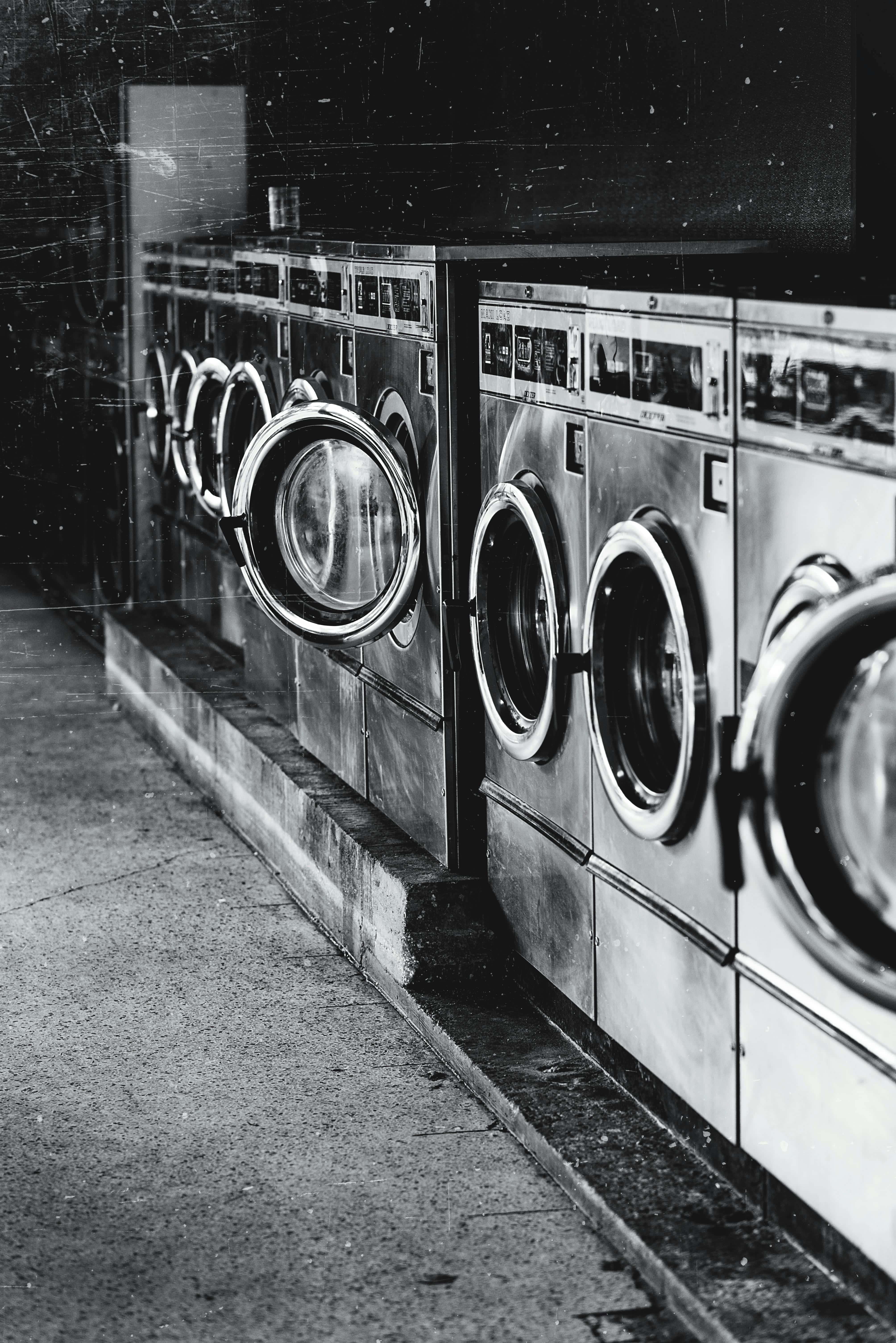 vintage industrial washing machines, dimly lit laundromat, cracked concrete floor, 5K Phone Wallpaper