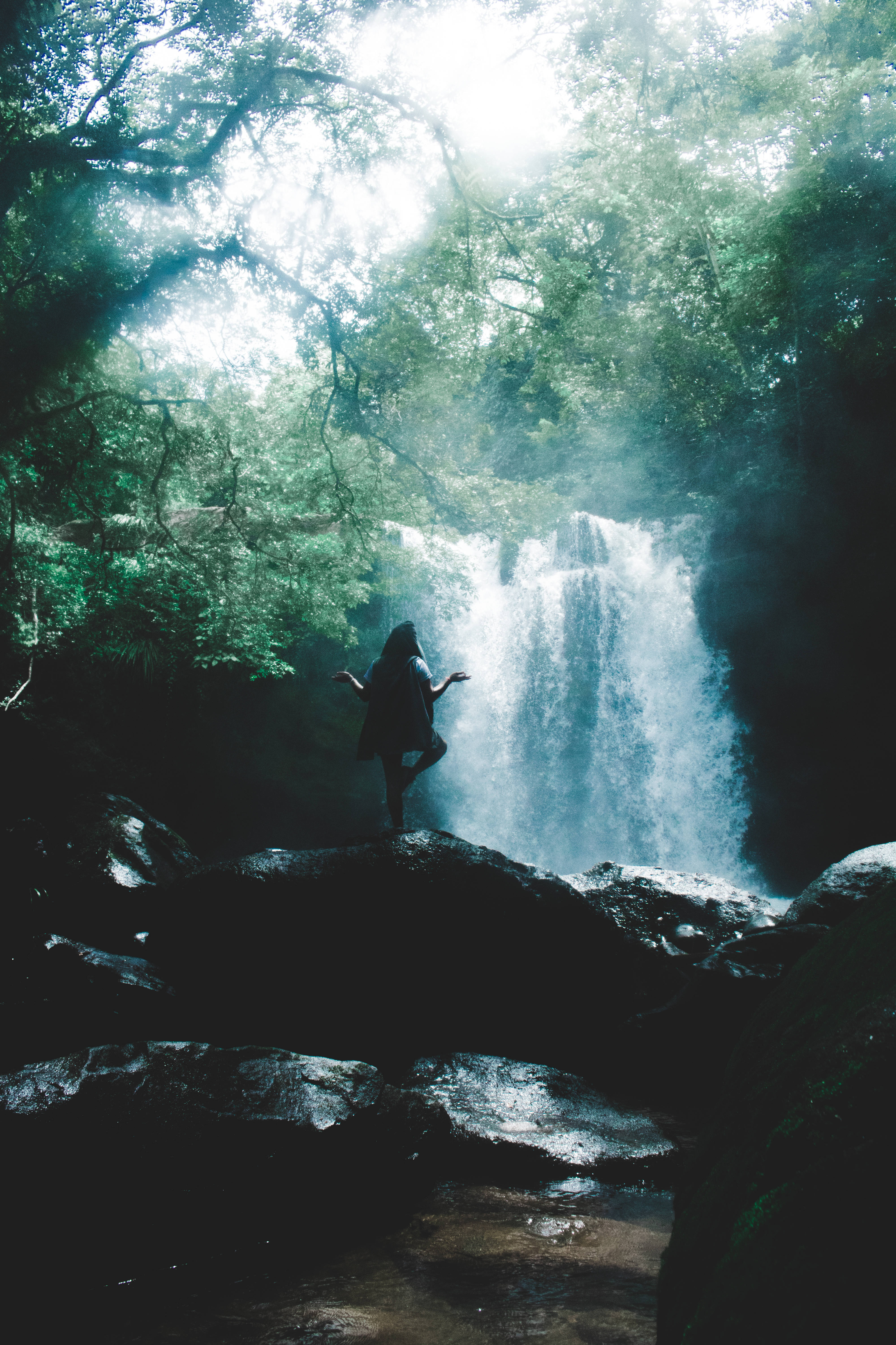 Waterfall, silhouetted person, rocks, 5K Phone Wallpaper