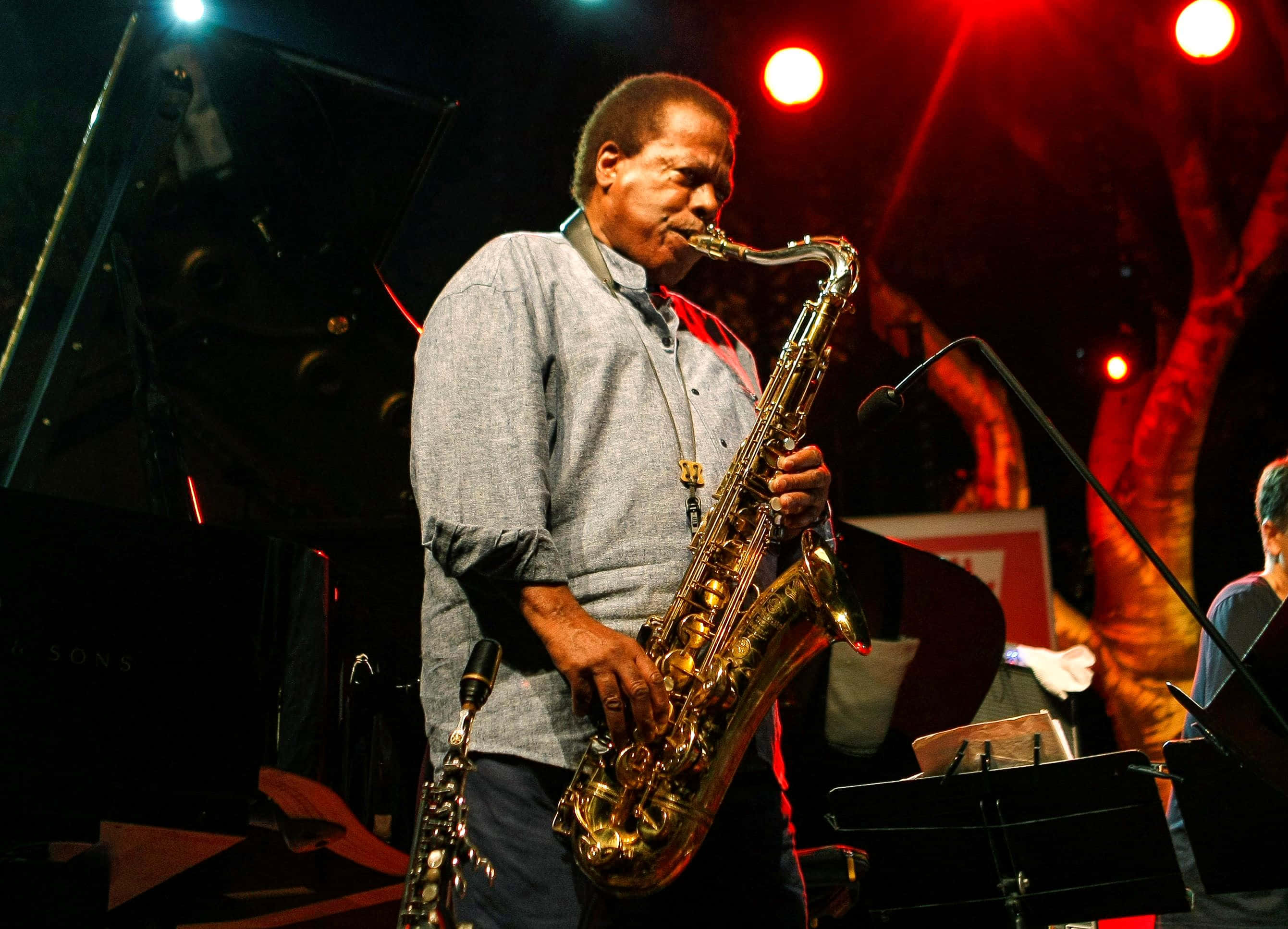 Wayne Shorter, golden saxophone, warm red stage lights, 2K Desktop Wallpaper