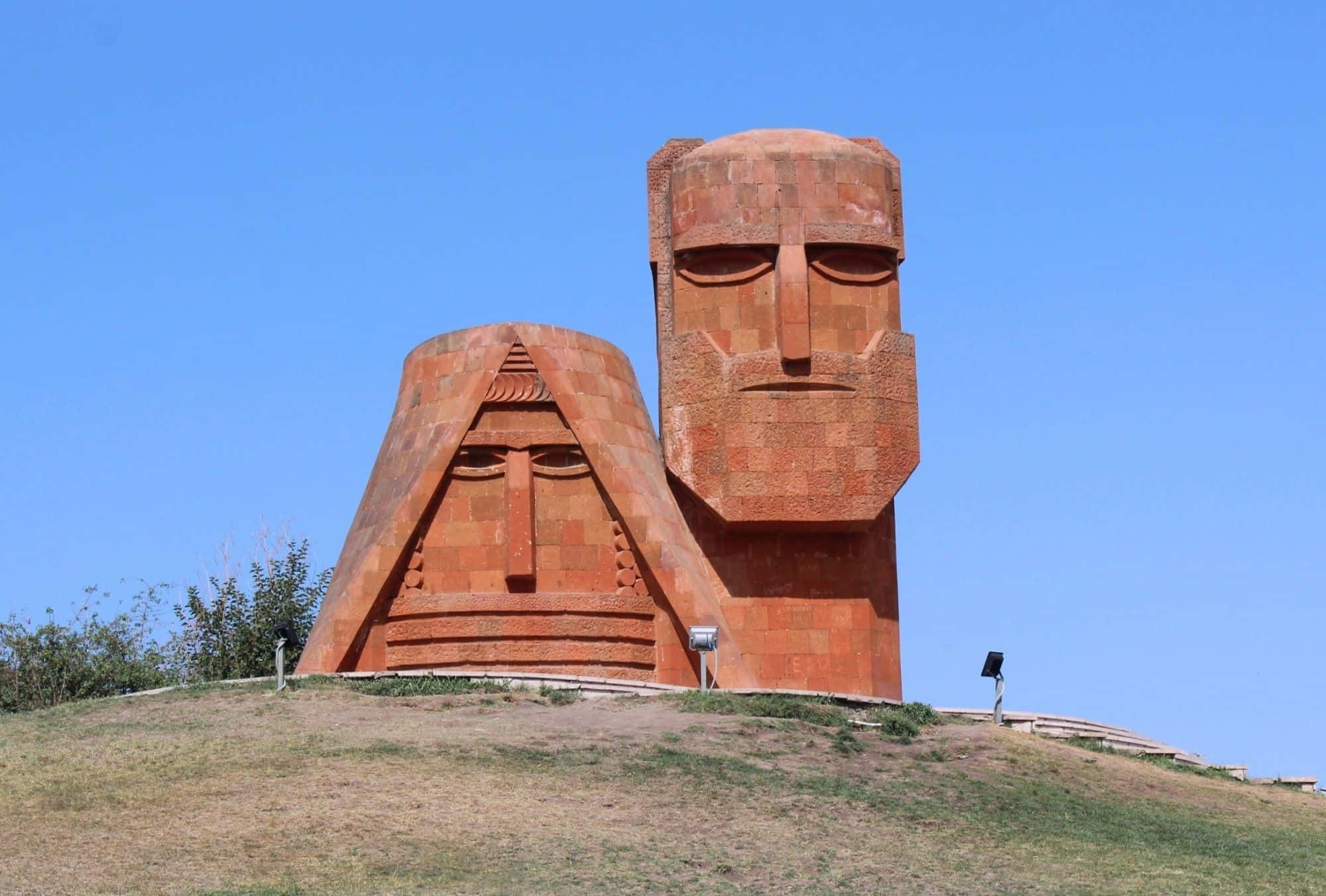 We Are Our Mountains, terracotta-colored stone heads, grassy hill, Full HD Desktop Wallpaper