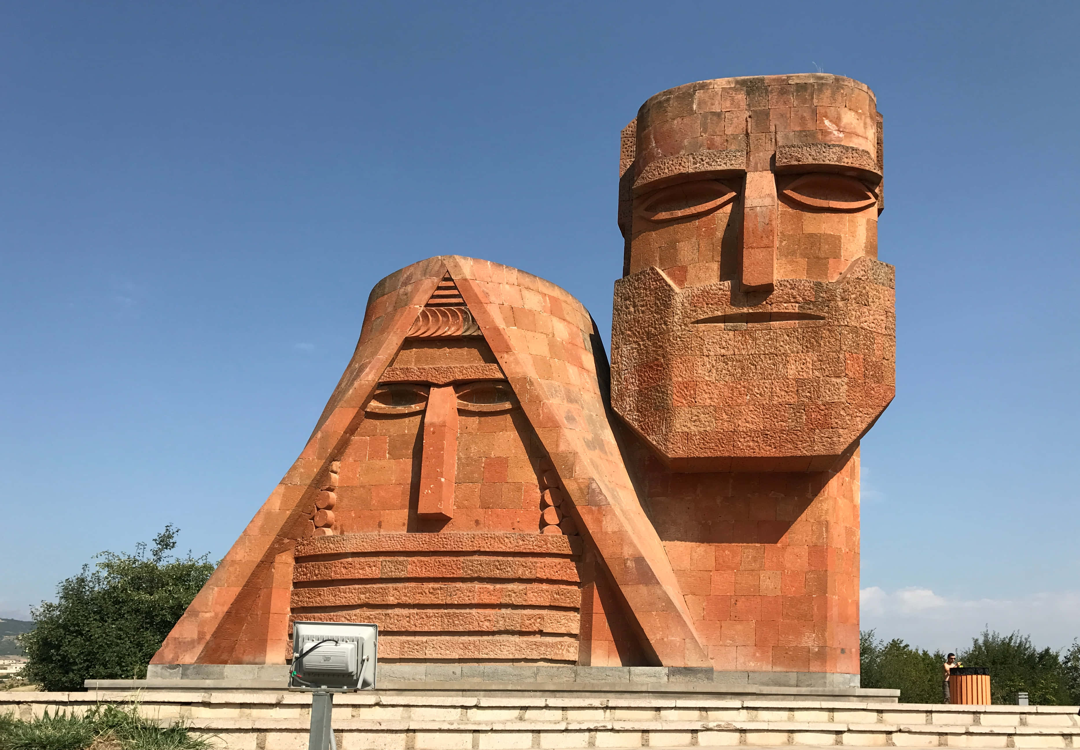 We Are Our Mountains, terracotta-colored stone heads, geometric features, 2K Desktop Wallpaper